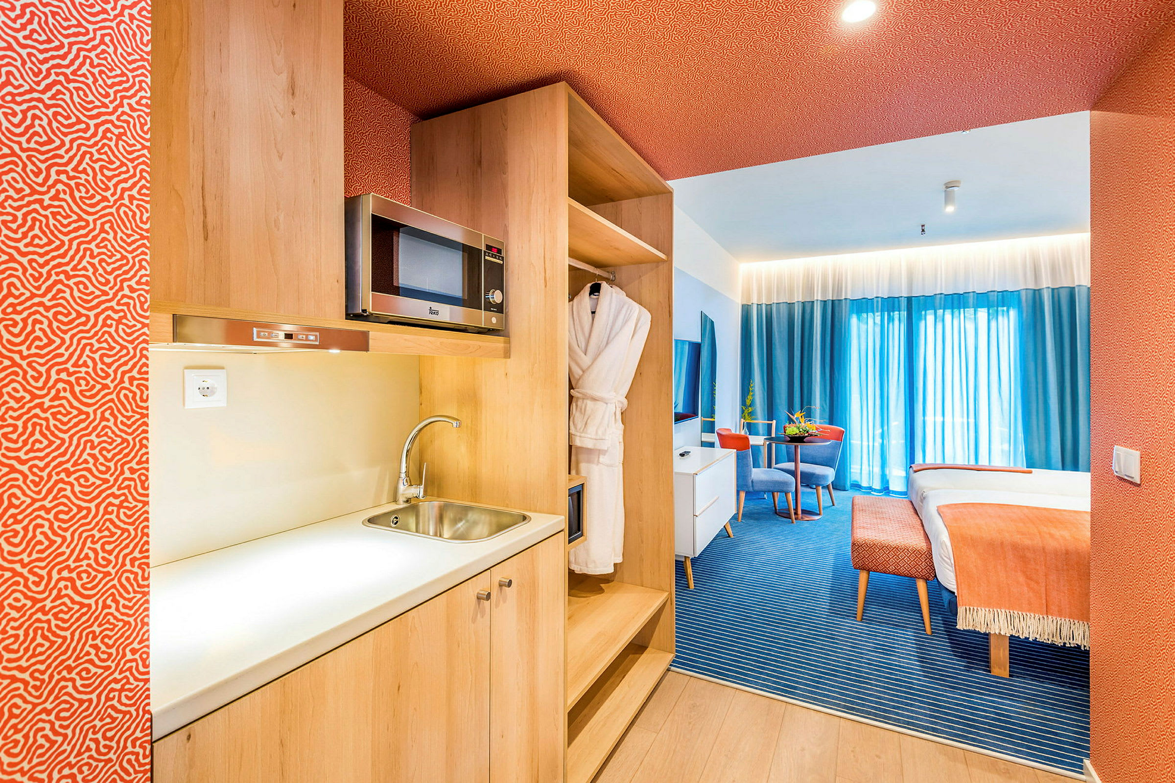 Hotellihuoneisto, jossa on keittiösyvennys, oleskelutila ja sänky. (Tekoälyn luoma teksti)