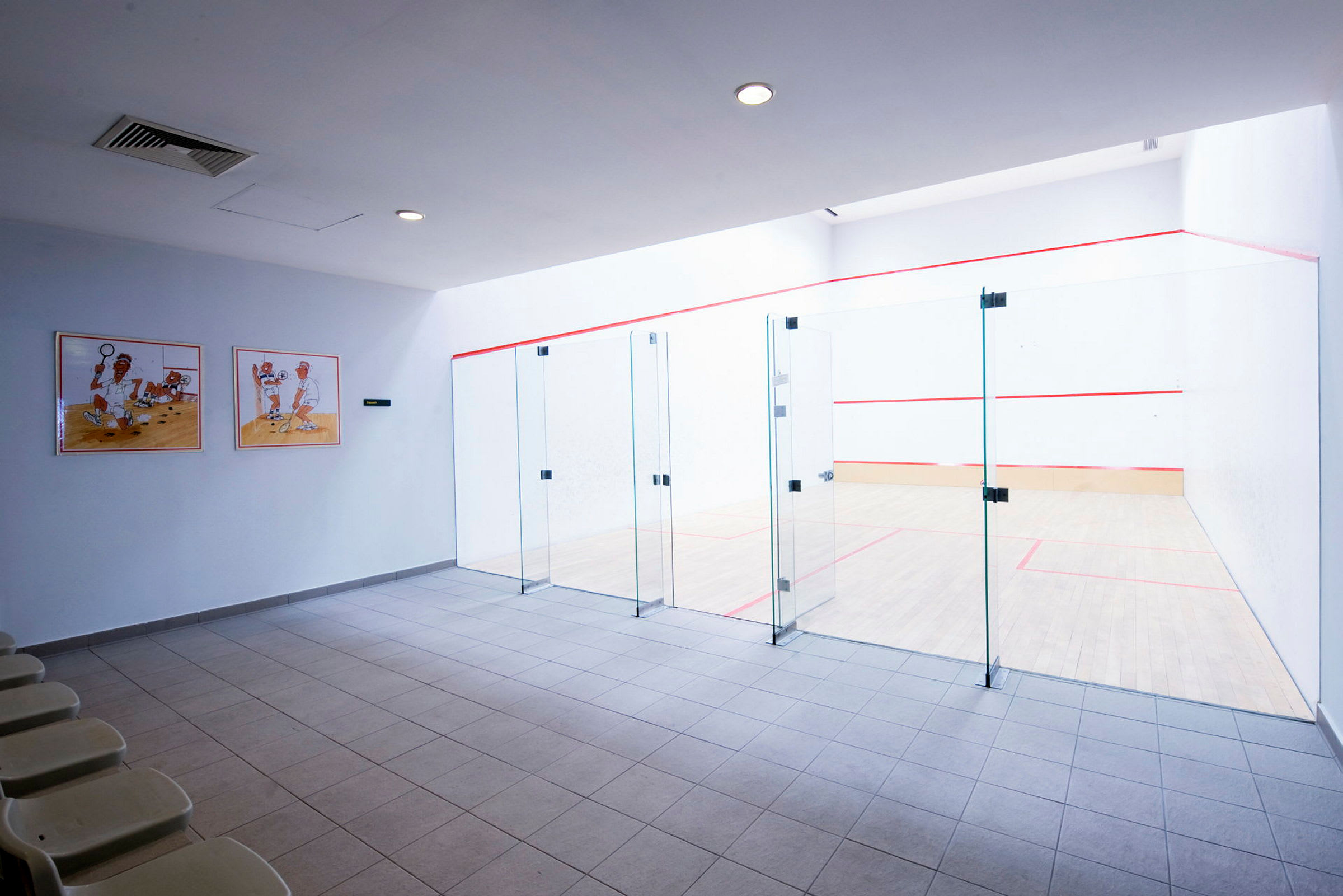 Kuva squash-hallista, jossa on lasiseinät ja istuimia. (Tekoälyn luoma teksti)