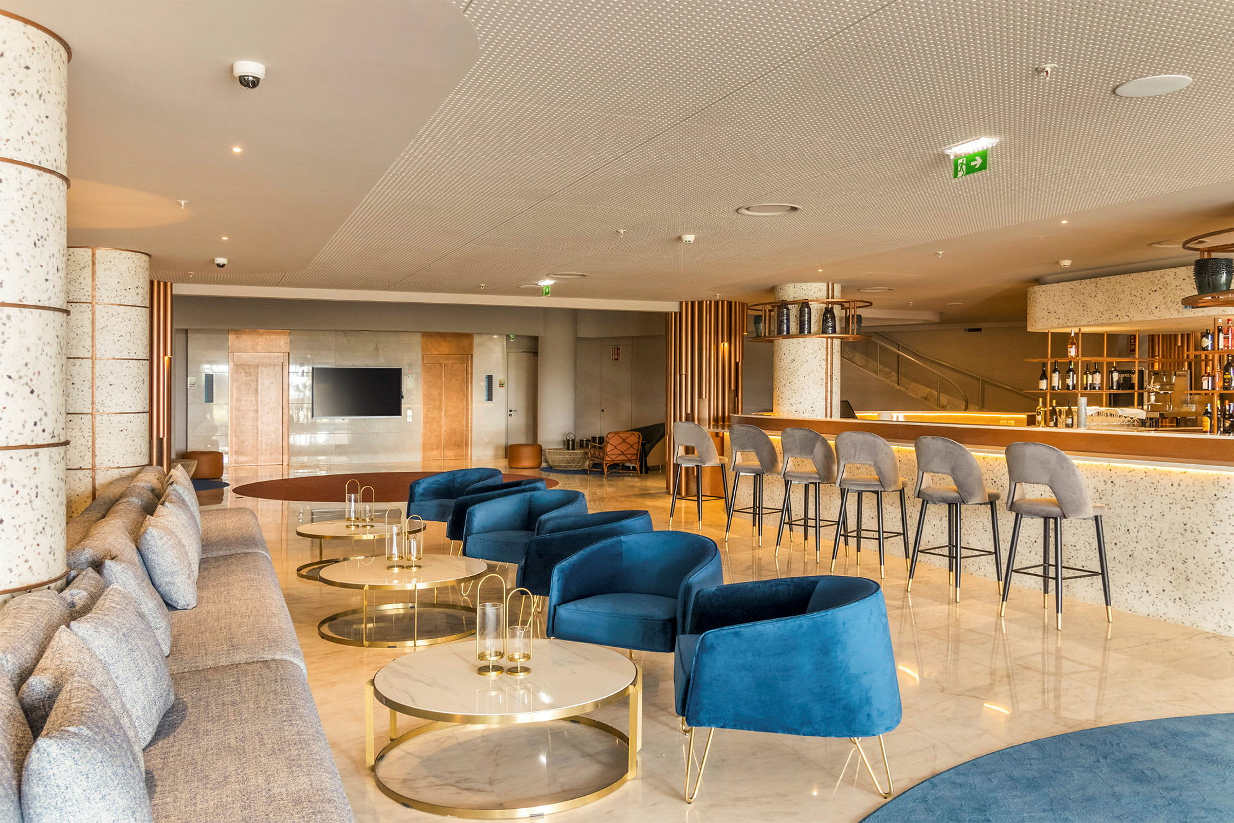 Moderni hotellihuone, jossa on sinisiä nojatuoleja, sohvia ja baarialue. (Tekoälyn luoma teksti)