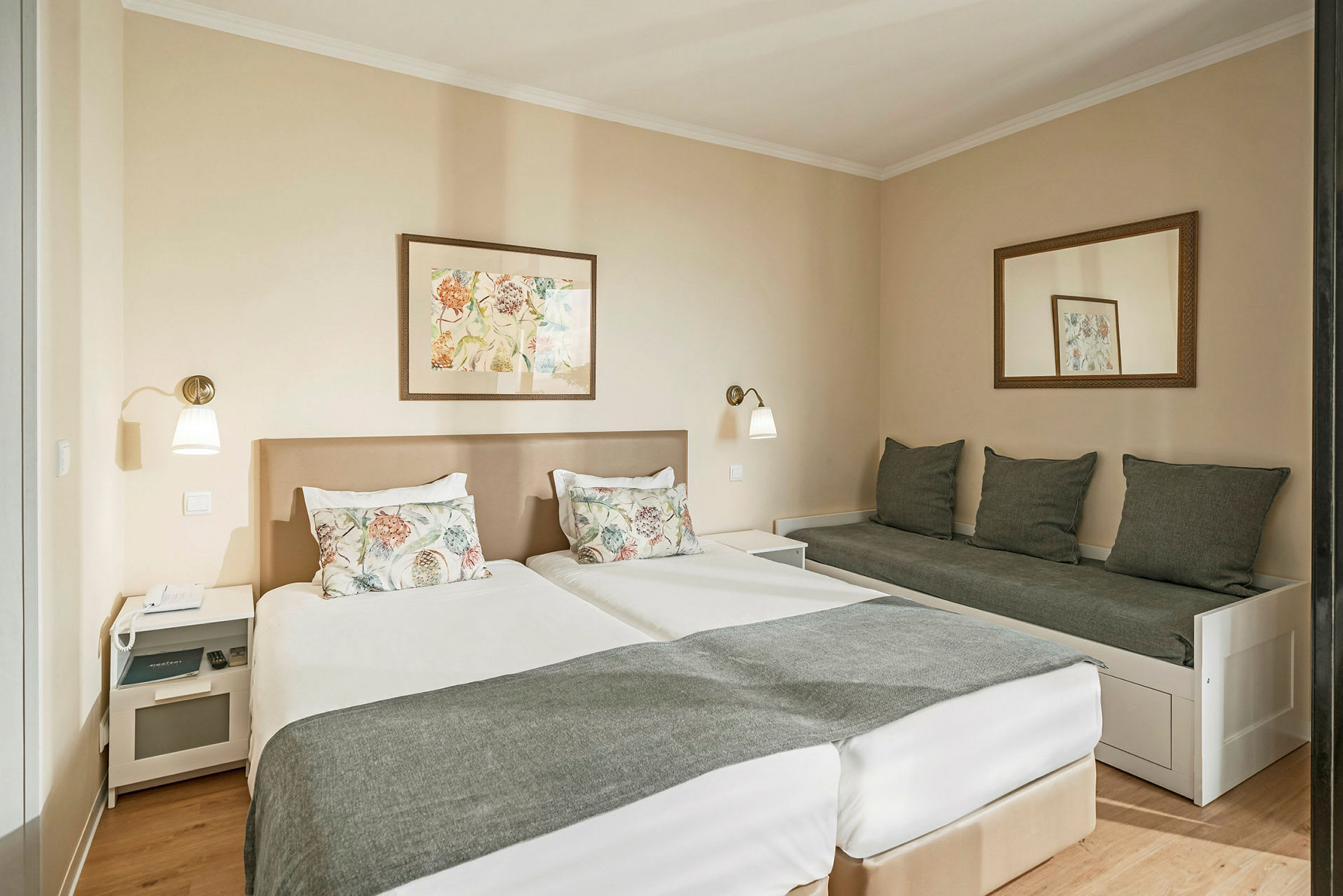 Hotellihuone, jossa kaksi sänkyä ja sohva vierekkäin. (Tekoälyn luoma teksti)