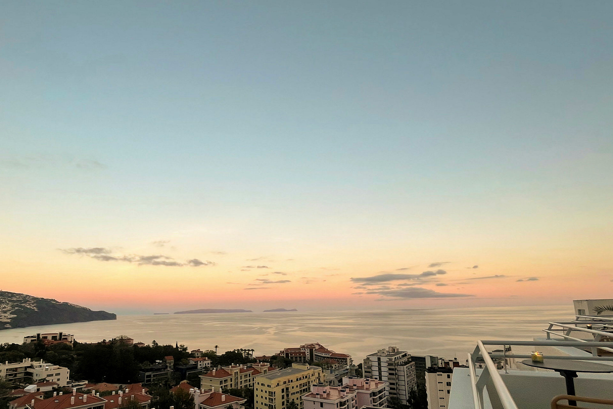 Kuva rannikkokaupungista, etualalla rakennuksia ja taustalla meri auringonlaskun aikaan. (Tekoälyn luoma teksti)