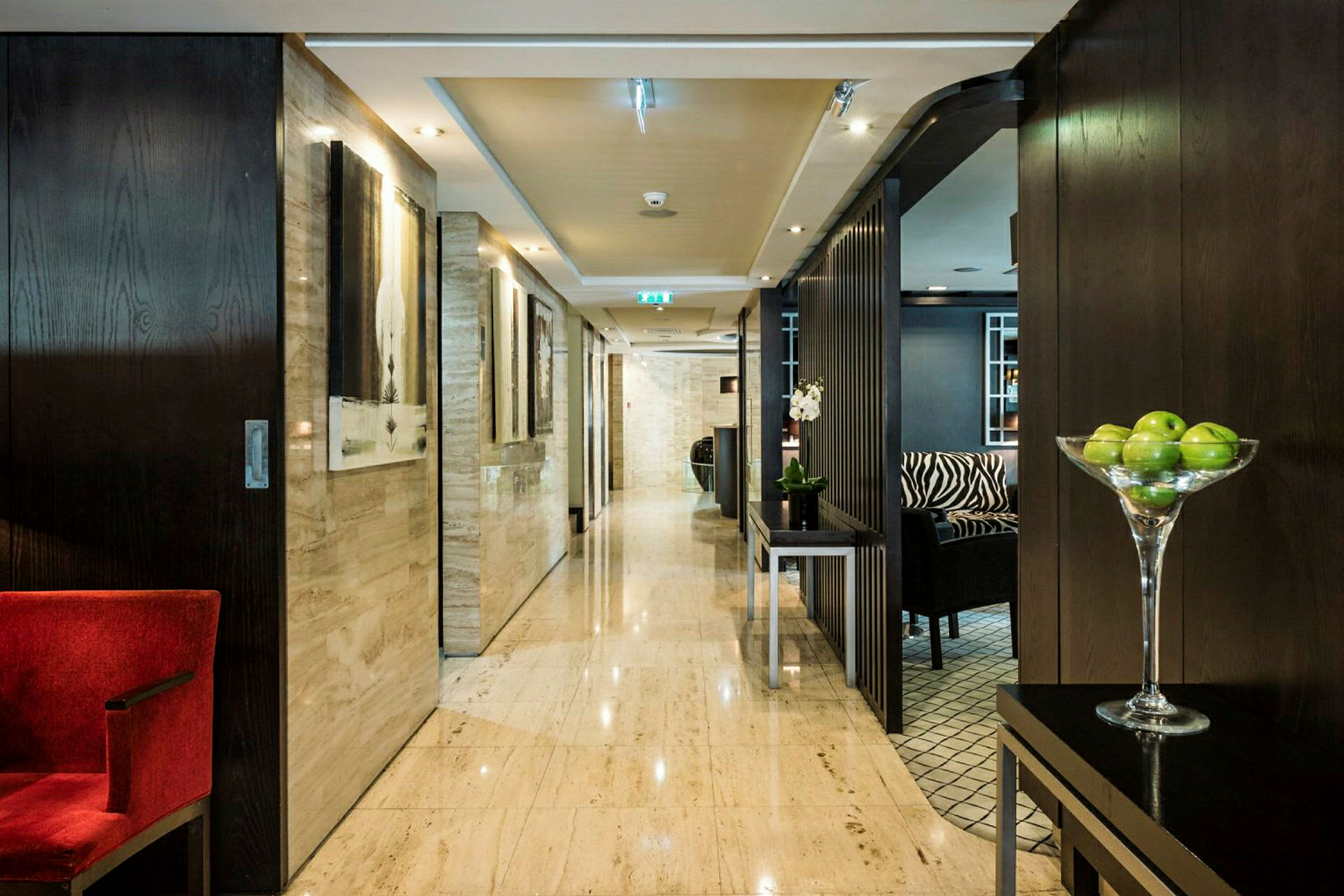 Hotellikäytävä modernilla sisustuksella ja vihreitä omenoita kulhossa. (Tekoälyn luoma teksti)