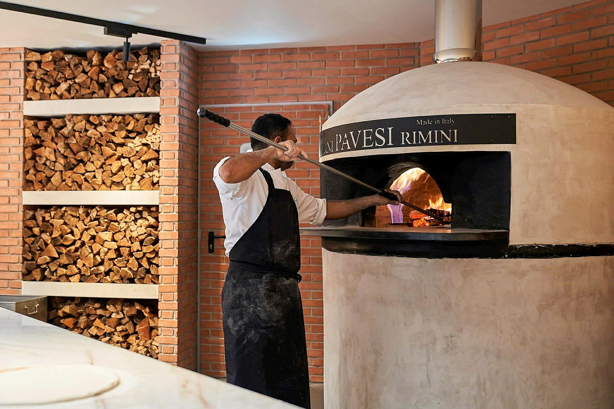 Henkilö valmistaa pizzaa puulämmitteisessä uunissa. (Tekoälyn luoma teksti)