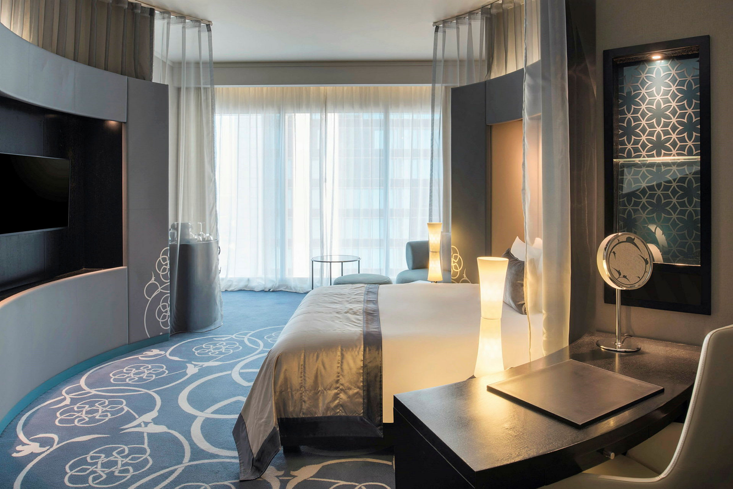 Hotellihuone modernilla sisustuksella, sänky ja kirjoituspöytä. (Tekoälyn luoma teksti)