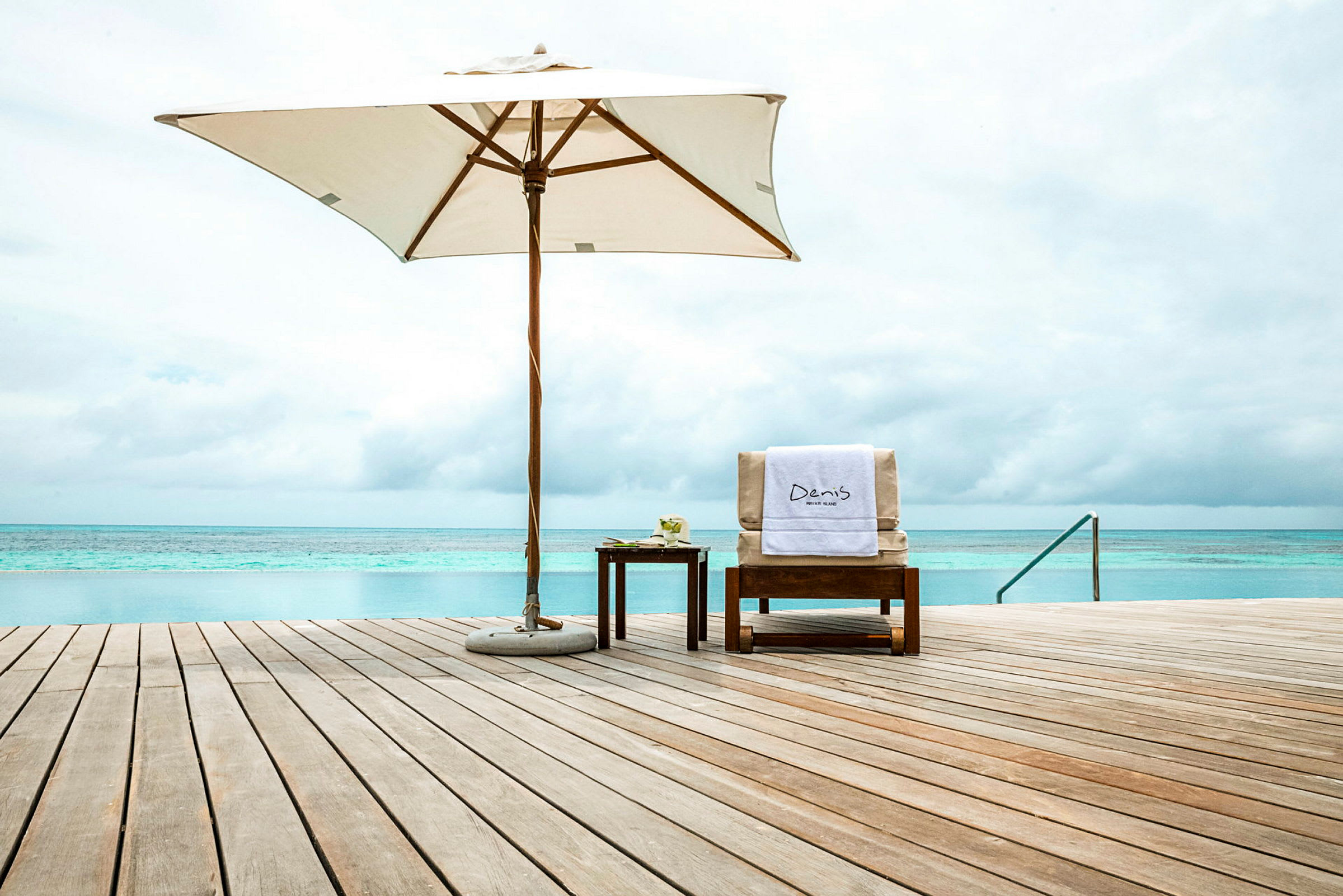 Puisella terassilla aurinkotuoli, varjo ja meri taustalla. (Tekoälyn luoma teksti)
