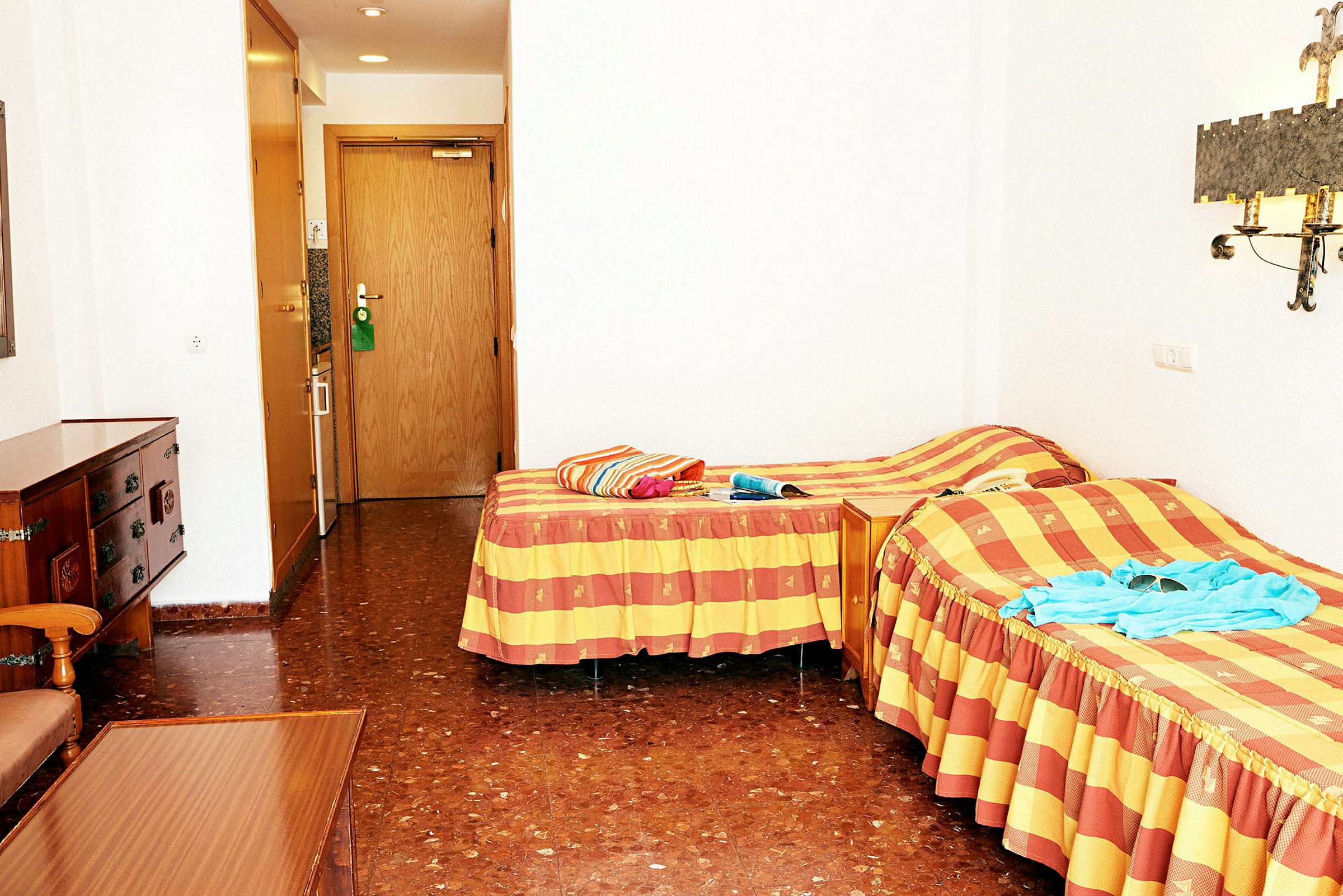 Hotellihuone, jossa kaksi yhden hengen vuodetta ja ovi kylpyhuoneeseen. (Tekoälyn luoma teksti)