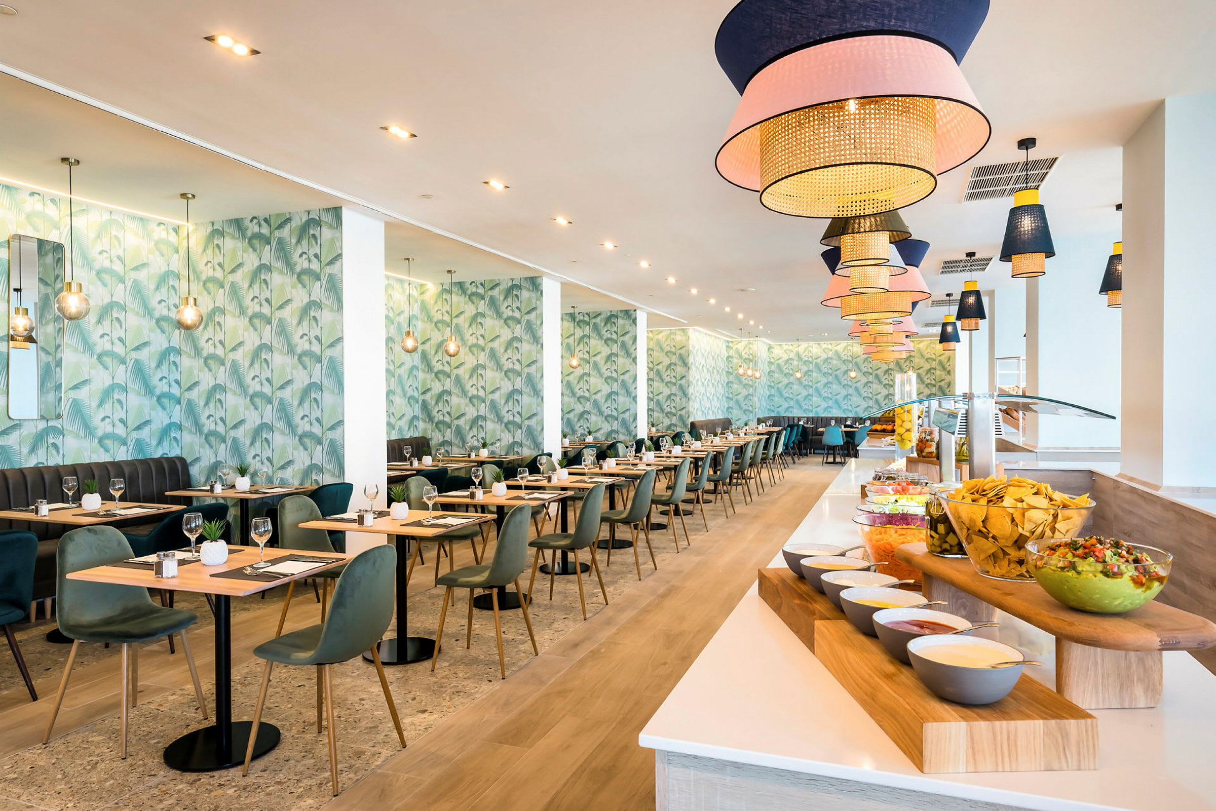 Moderni ravintola, jossa on pöytiä ja tuoleja. Oikealla puolella on buffet, jossa on erilaisia ruokia ja lisukkeita. (Tekoälyn luoma teksti)