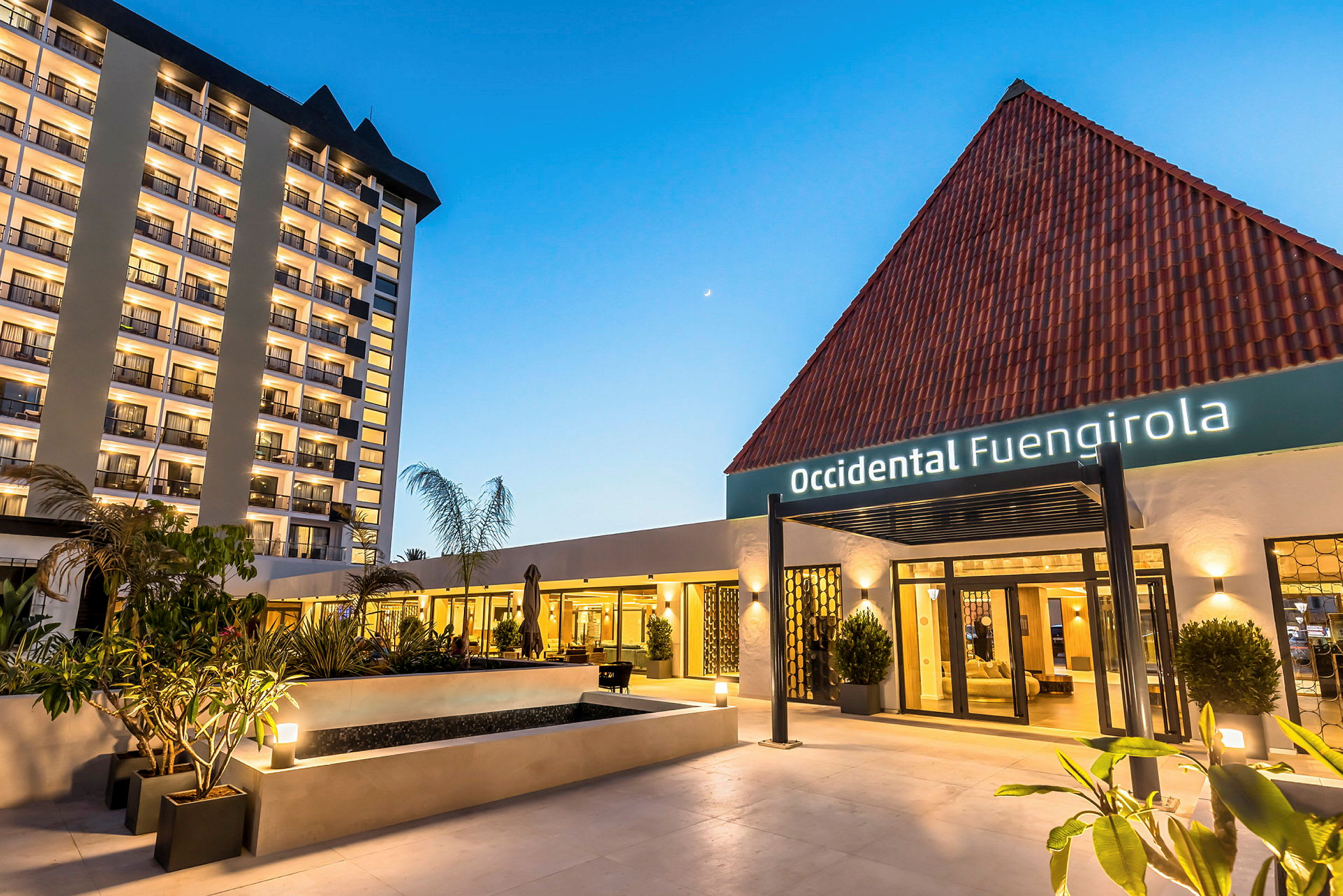 Hotellirakennus nimeltä Occidental Fuengirola, valaistut julkisivut ja sisäänkäynti kasvien ympäröimänä. (Tekoälyn luoma teksti)