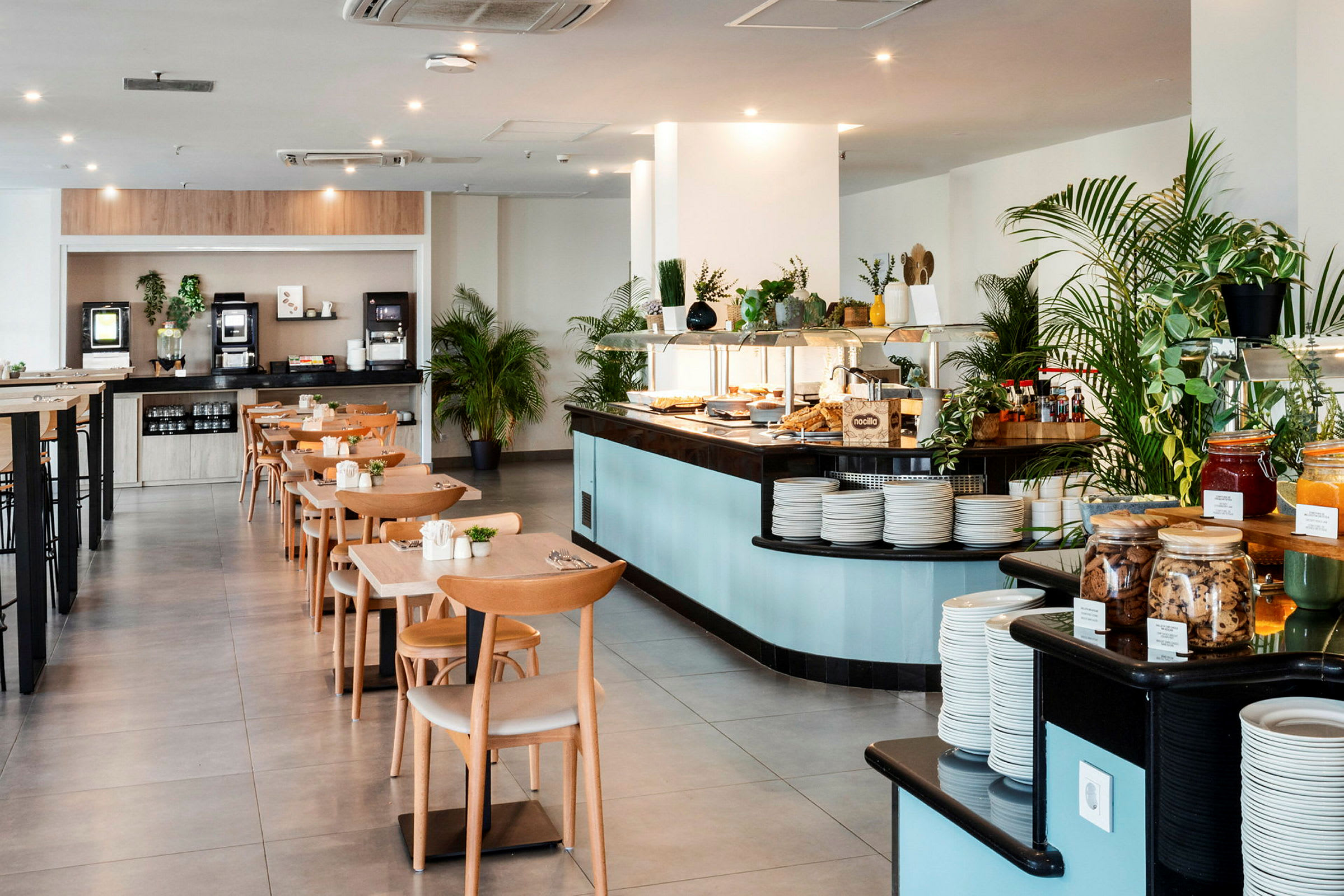 Tilava ravintola-alue, jossa pöytiä ja tuoleja sekä buffet, jossa on erilaisia ruokia. (Tekoälyn luoma teksti)