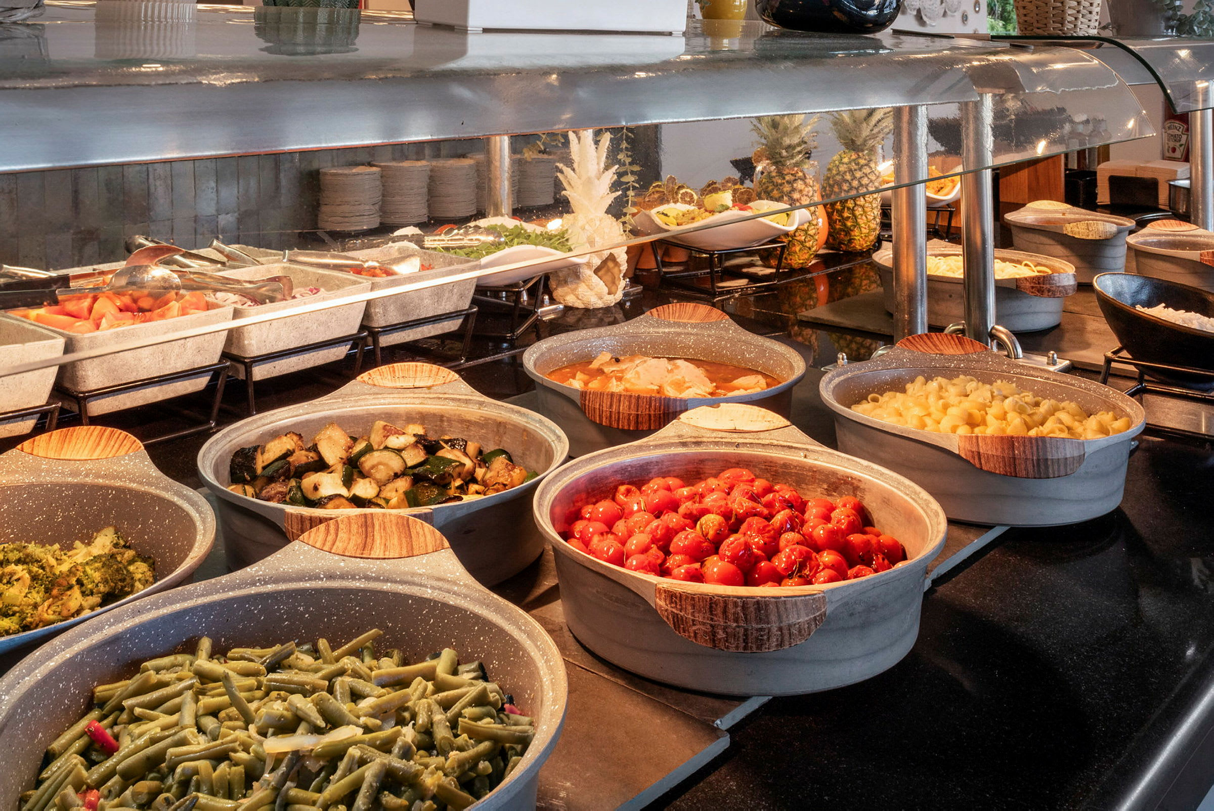 Buffet, jossa erilaisia ruokia, kuten vihanneksia ja pastaa. (Tekoälyn luoma teksti)