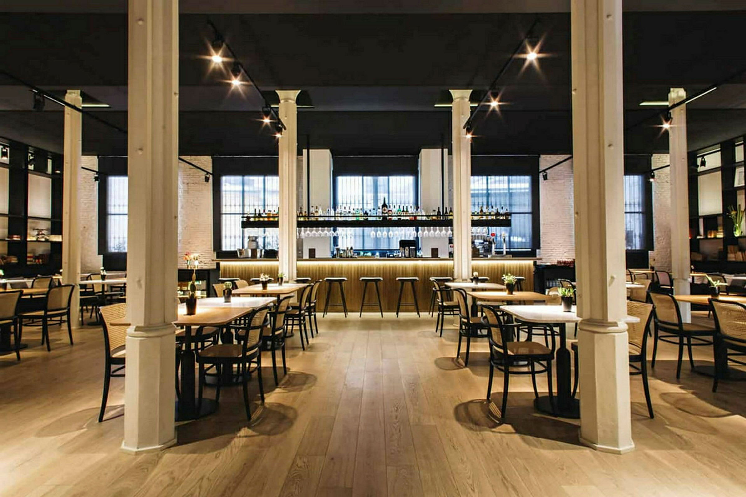 Tyylikäs ravintola, jossa on pöytiä ja tuoleja sekä hyvin valaistu baaritiski taustalla. (Tekoälyn luoma teksti)