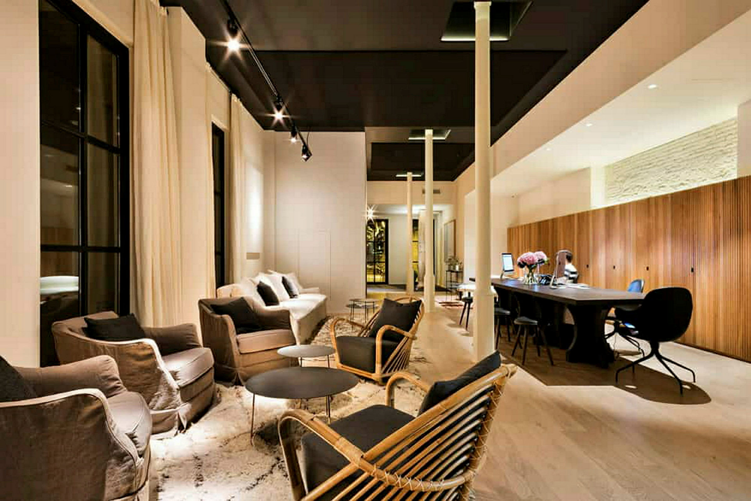 Modernisti sisustettu lounge, jossa on sohvia, nojatuoleja, pöytiä ja työtila. (Tekoälyn luoma teksti)