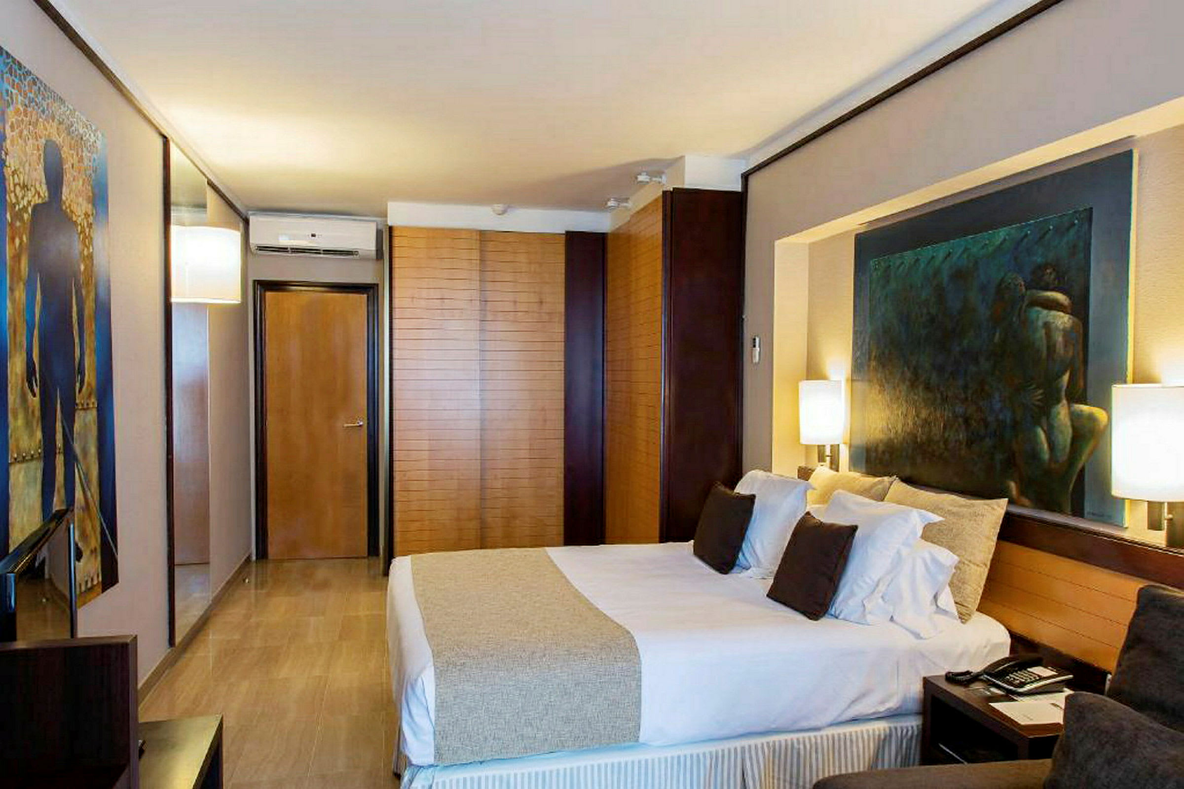 Moderni hotellihuone, jossa parivuode, seinillä maalauksia ja tyylikäs sisustus. (Tekoälyn luoma teksti)