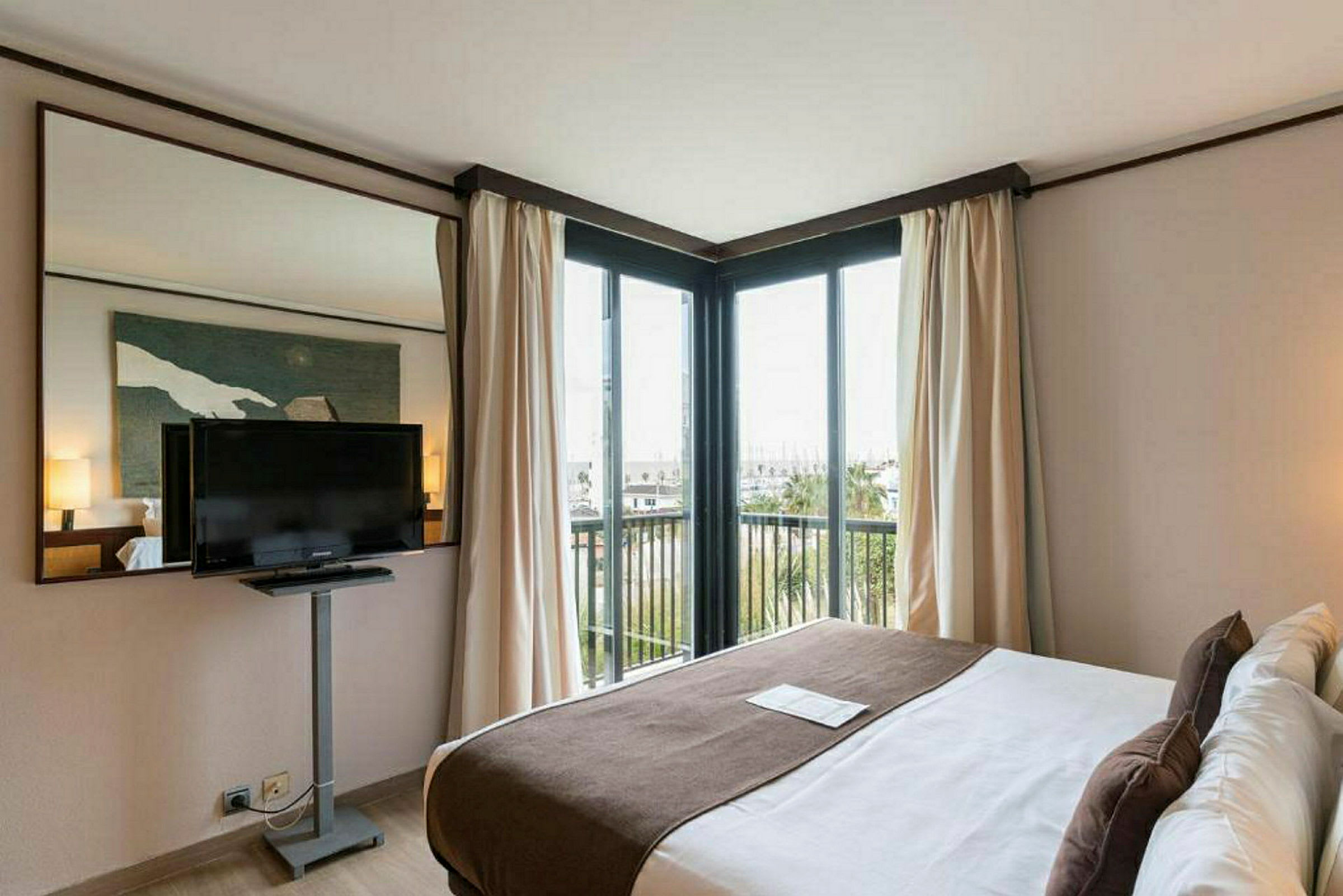 Hotellihuone, jossa on parivuode, seinään kiinnitetty TV ja suuret ikkunat näkymällä. (Tekoälyn luoma teksti)
