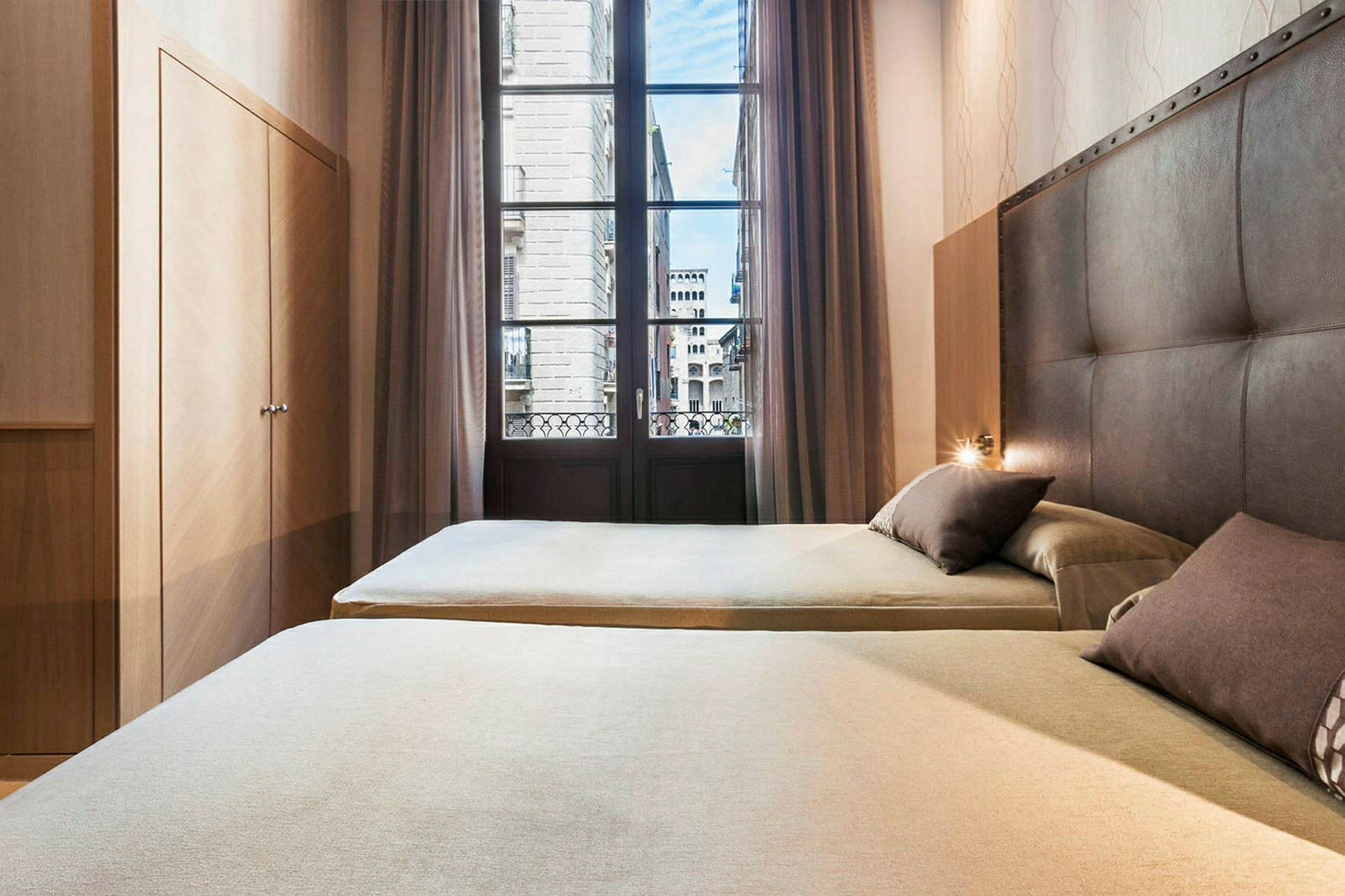 Hotellihuone, jossa on kaksi vuodetta, kaappi ja suuri ikkuna näkymällä kaupunkiin. (Tekoälyn luoma teksti)
