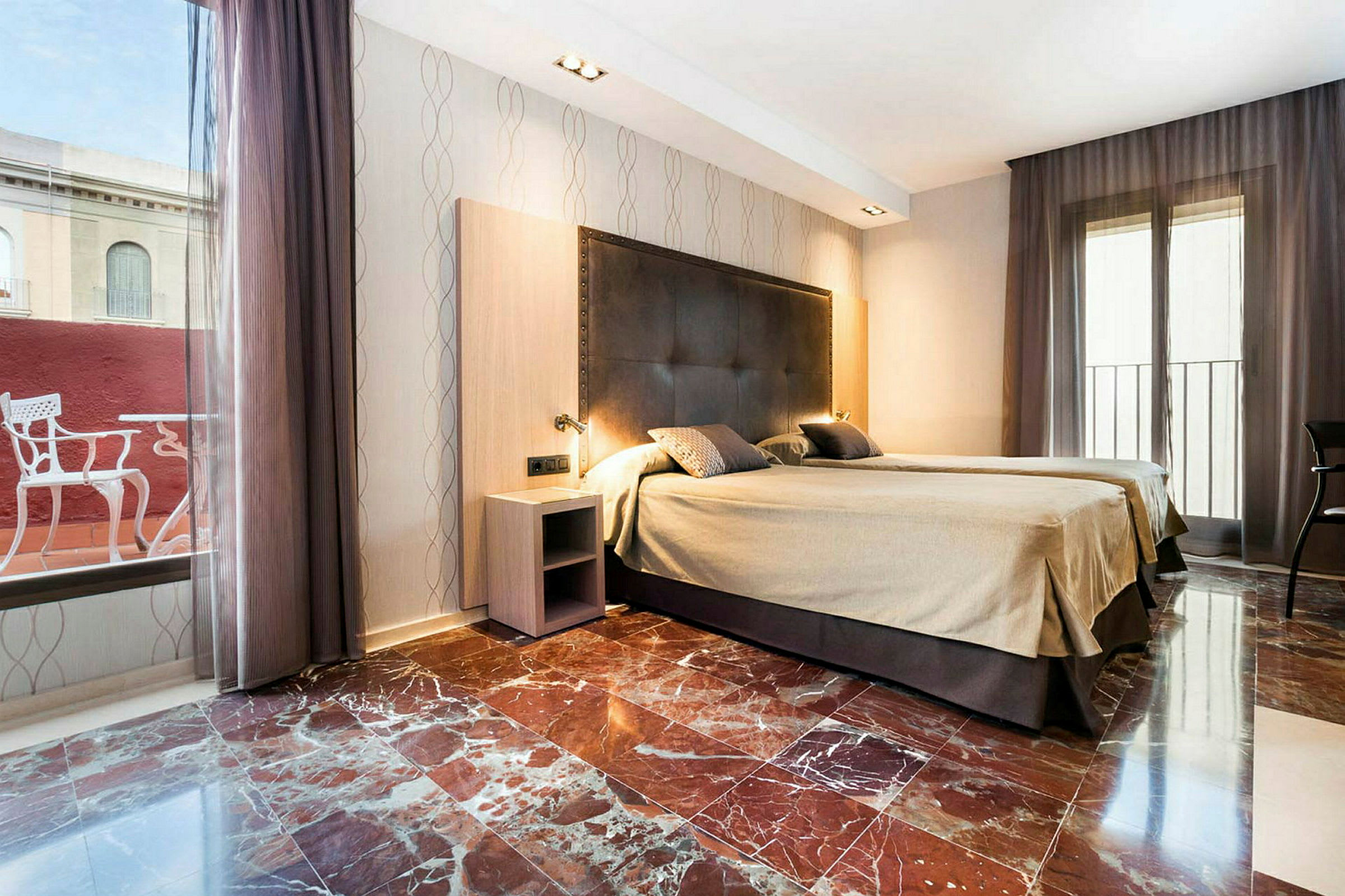 Hotellihuone, jossa on kaksi erillistä vuodetta, marmorilattia ja suuret verhoilla varustetut ikkunat. (Tekoälyn luoma teksti)