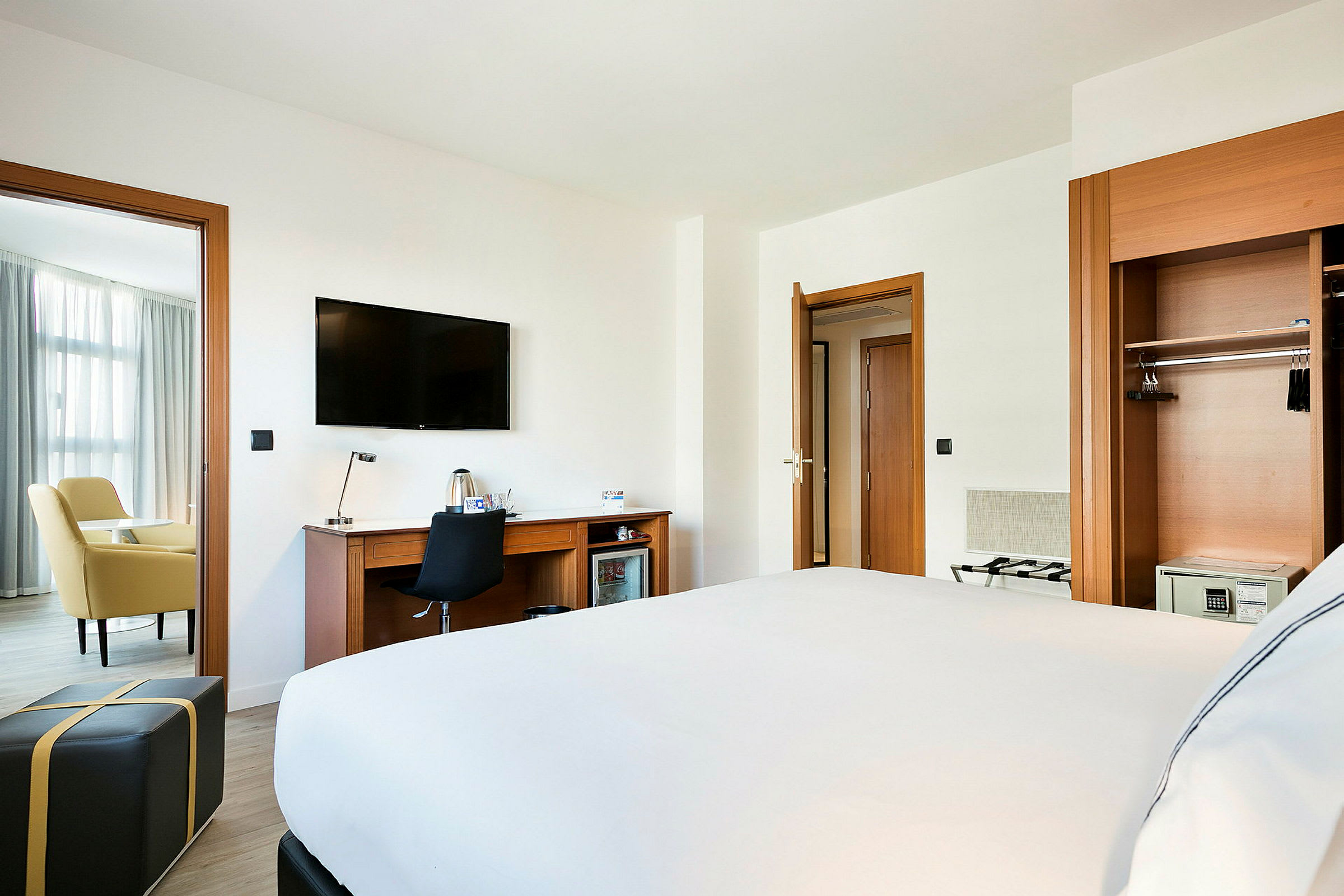 Hotellihuone, jossa sänky, kirjoituspöytä, televisio ja oleskelutila. (Tekoälyn luoma teksti)