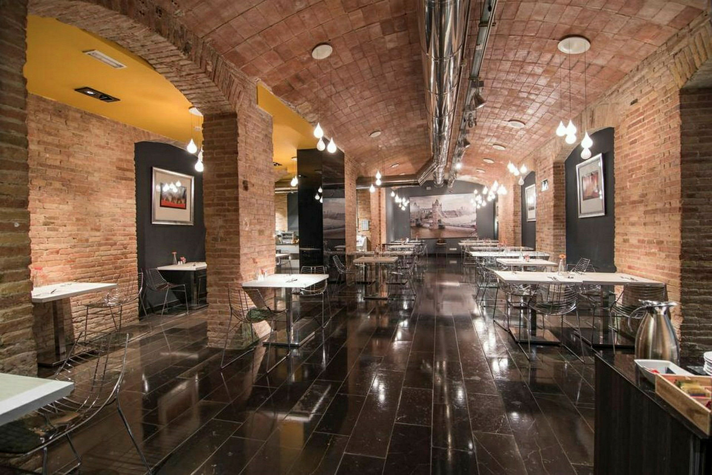 Ravintola-alue tiiliholveilla, kiiltävillä lattioilla ja modernilla sisustuksella. (Tekoälyn luoma teksti)
