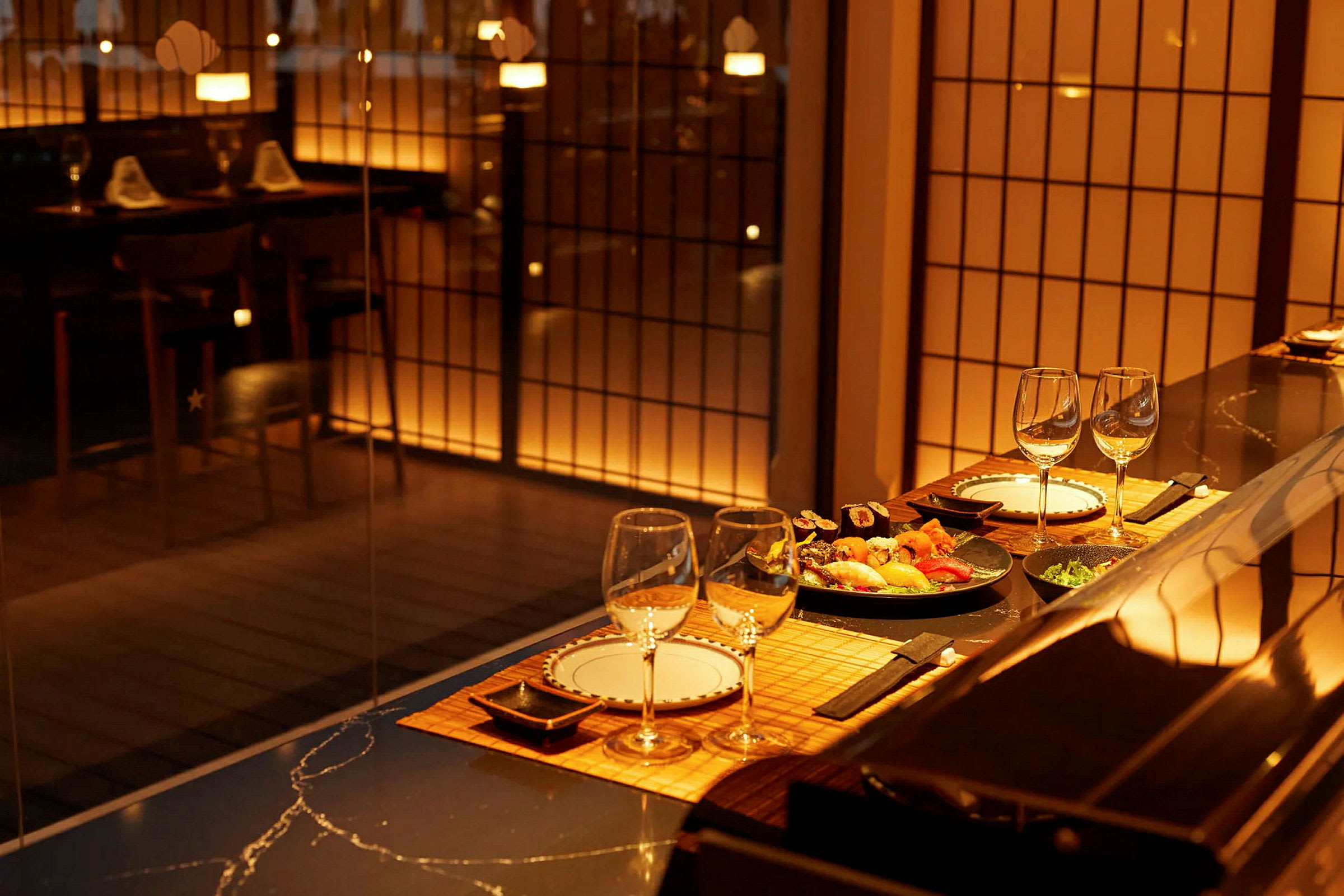 Tyylikäs ravintola, jossa on katettu pöytä ja sushi tarjoiltuna, valaistu lämpimällä valolla. (Tekoälyn luoma teksti)