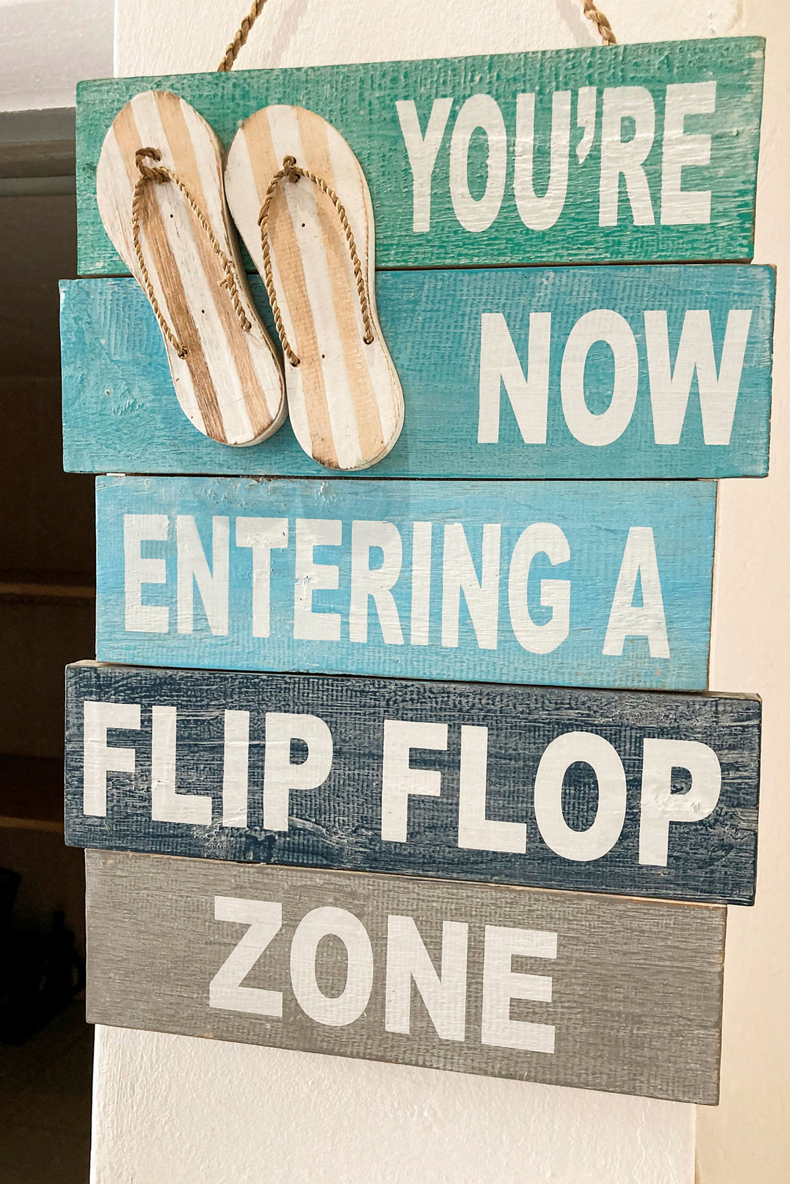 Kyltti, jossa lukee 'You're now entering a flip flop zone', ja yläosassa roikkuvat sandaalit. (Tekoälyn luoma teksti)