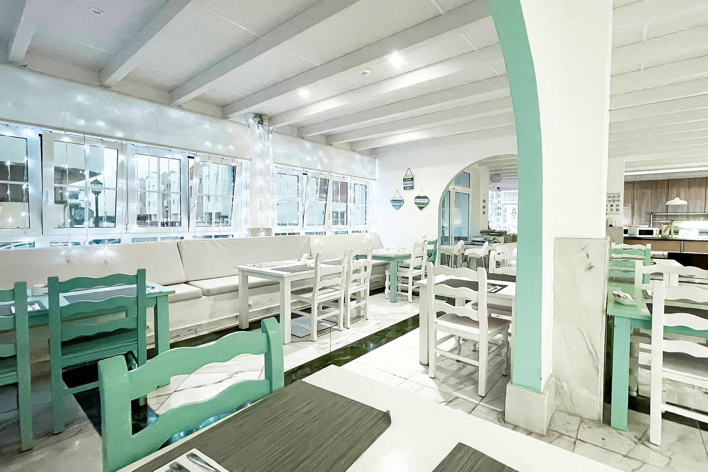 Valoisa ja tilava kahvila tai ravintola, jossa on valkoiset seinät ja vaaleanvihreät huonekalut. (Tekoälyn luoma teksti)