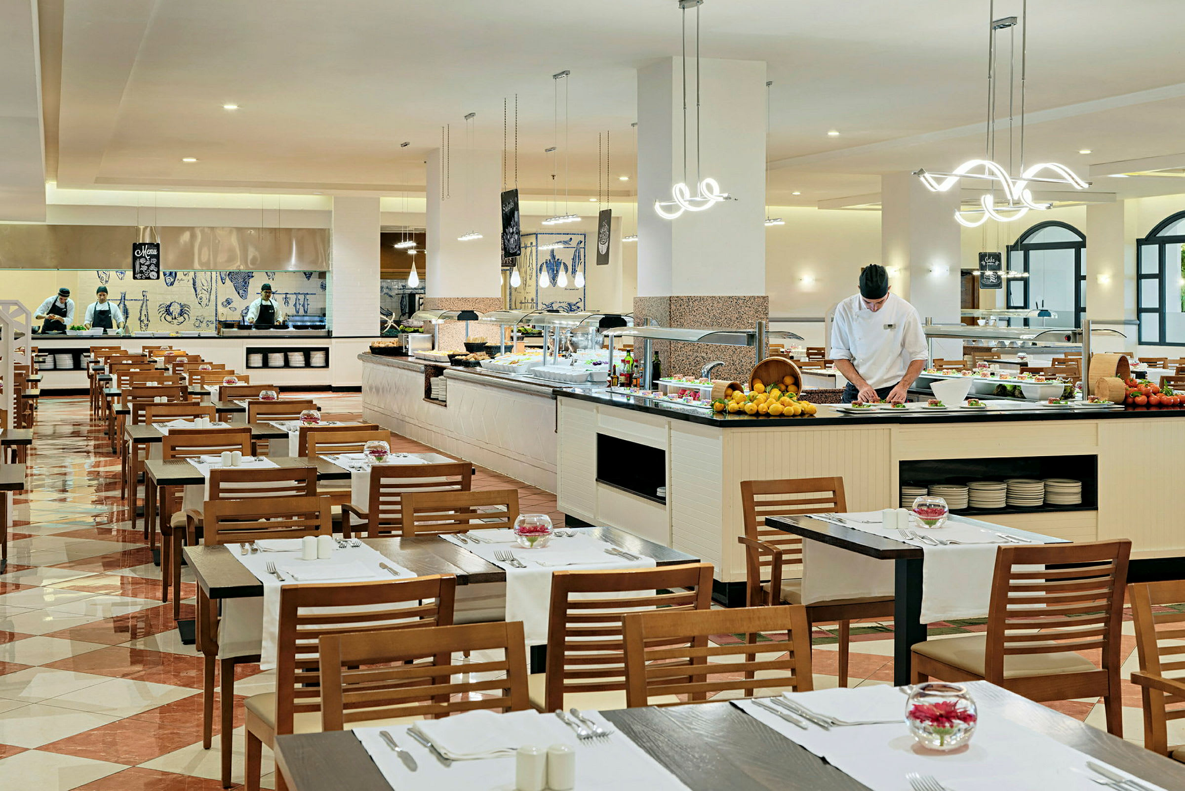 Ravintola, jossa on katettuja pöytiä ja buffetti. Henkilökunta työskentelee ruokapisteellä. (Tekoälyn luoma teksti)