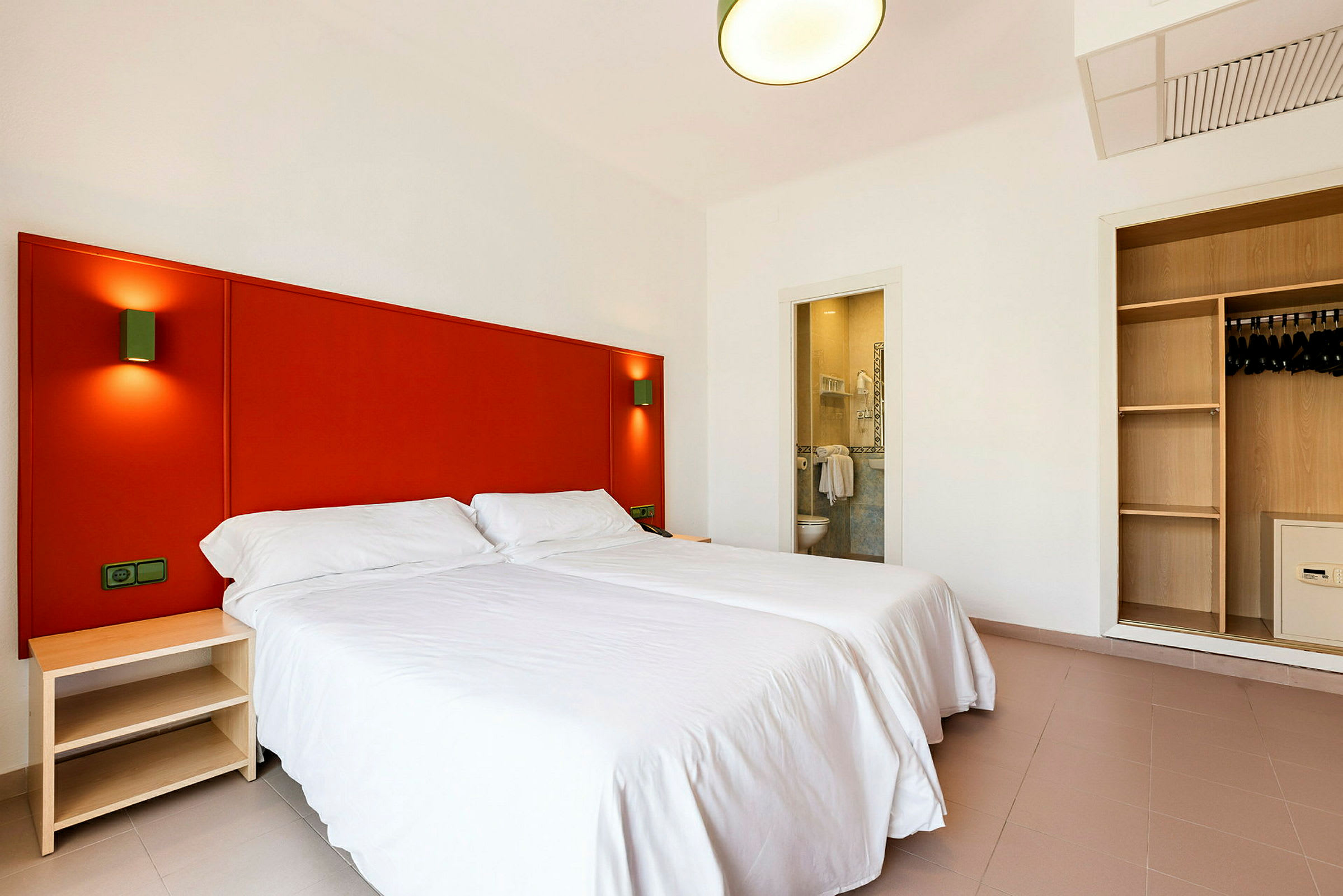 Hotellihuone, jossa kaksi yhden hengen vuodetta, vaatekaappi ja avoin kylpyhuone. (Tekoälyn luoma teksti)