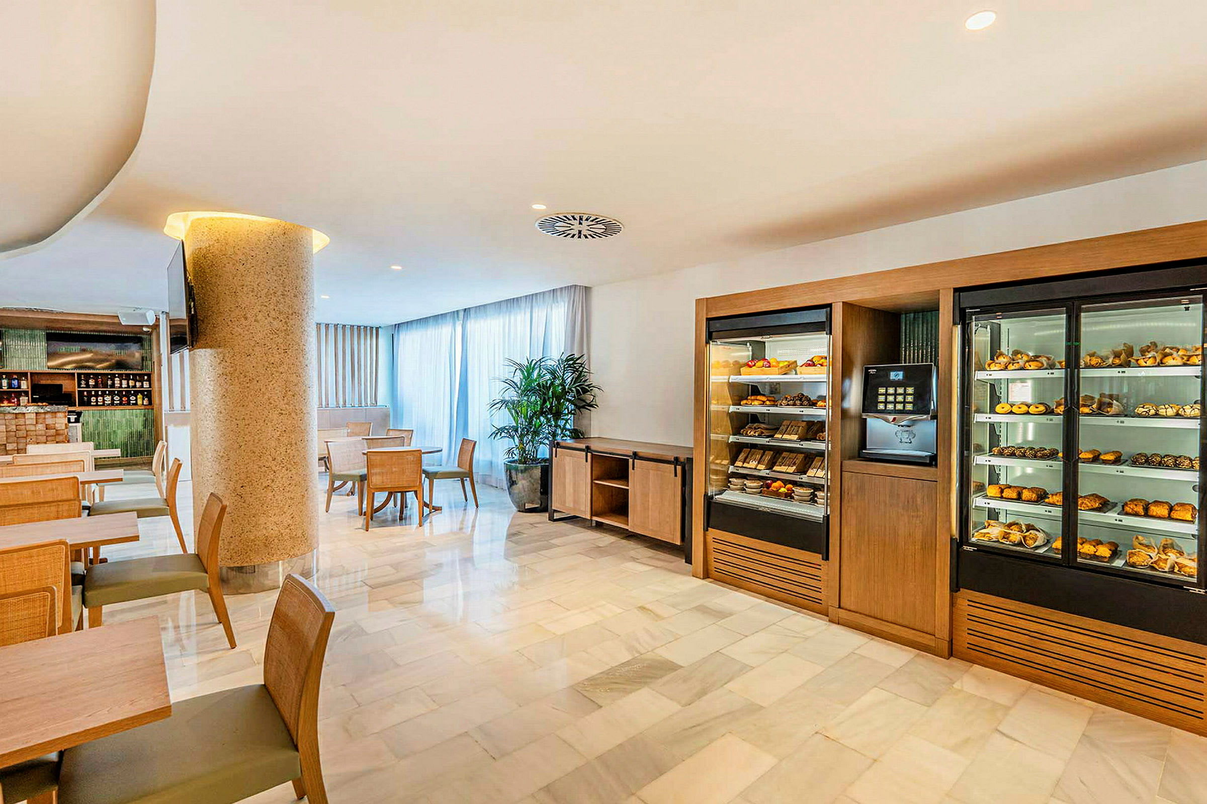 Hotelliravintola, jossa on pöytiä ja tuoleja sekä kaapit täynnä leivonnaisia ja hedelmiä. (Tekoälyn luoma teksti)
