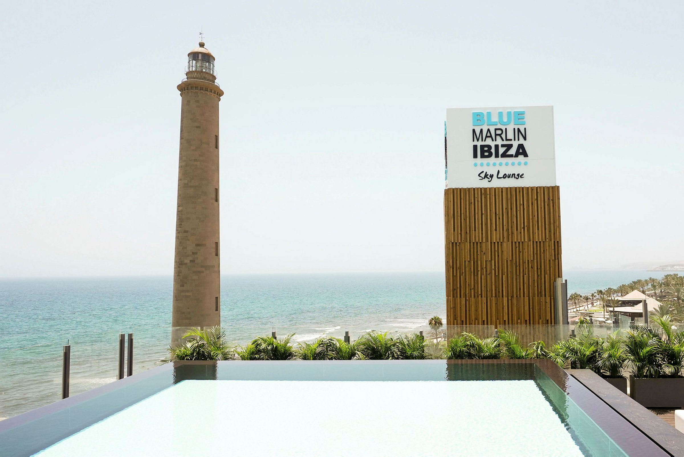 Majakka meren rannalla, vieressä kyltti, jossa lukee 'Blue Marlin Ibiza Sky Lounge'. (Tekoälyn luoma teksti)