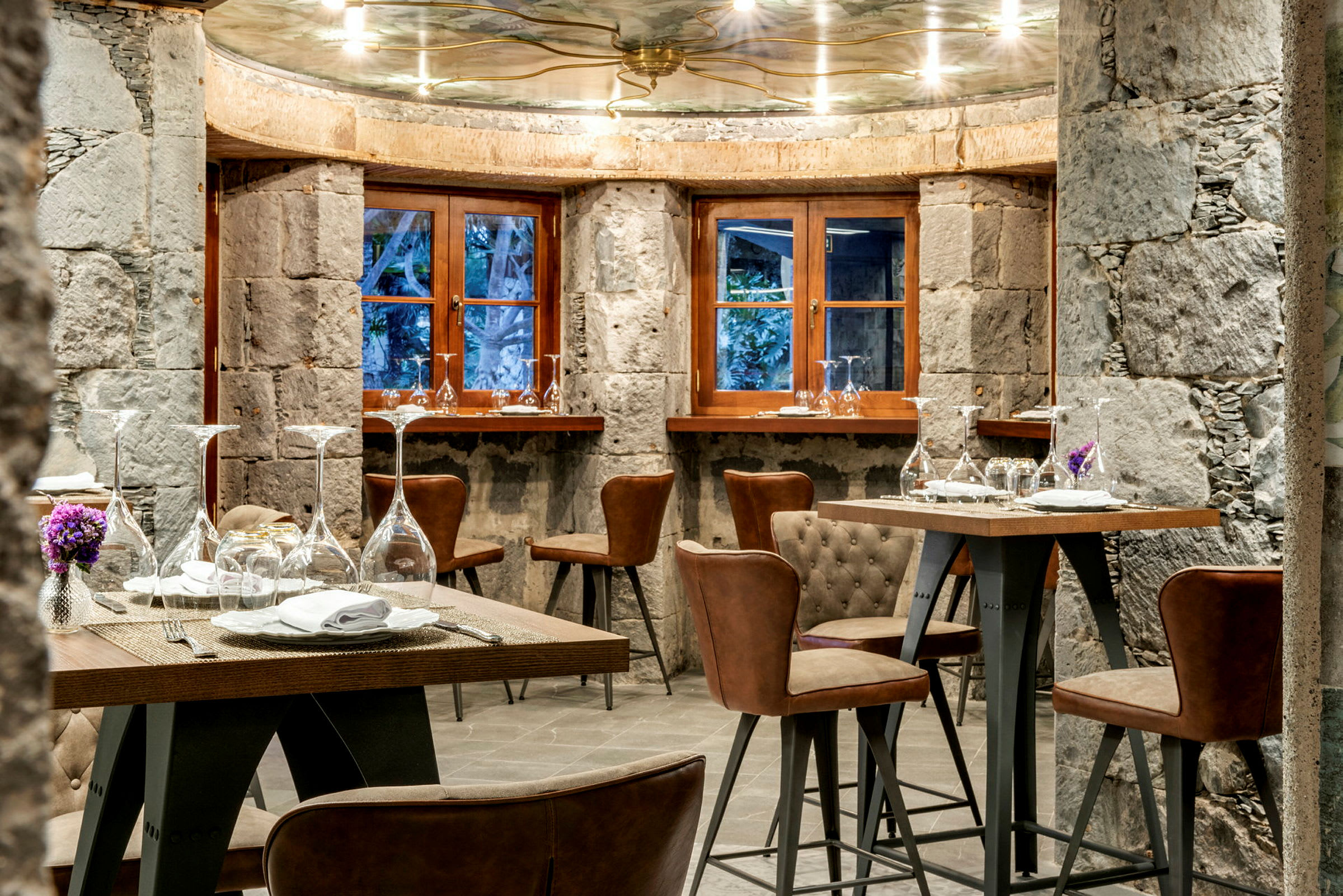 Ravintola, jossa on pöytiä ja tuoleja rustiikissa ympäristössä. (Tekoälyn luoma teksti)
