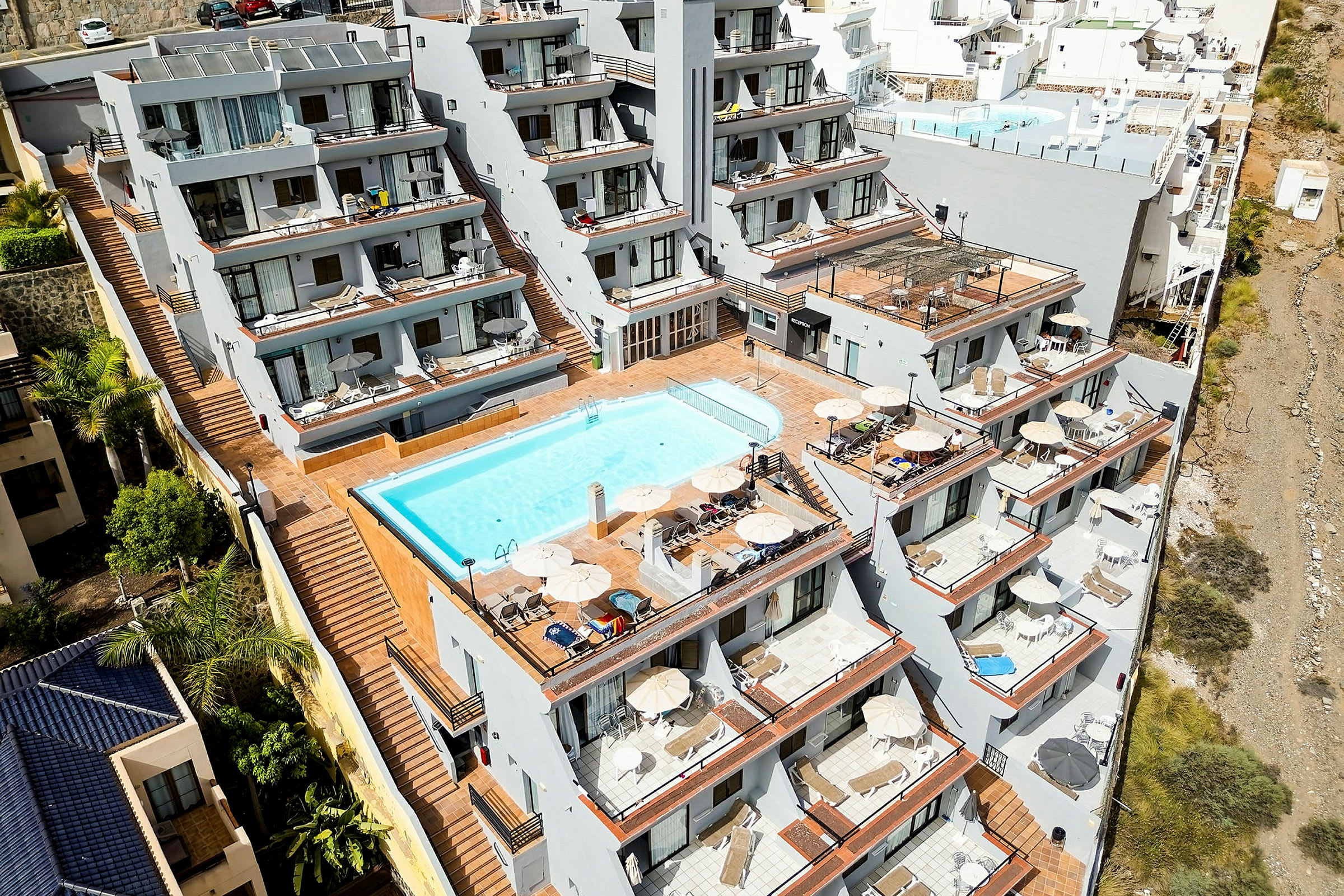 Hotellikompleksi, jossa on useita terasseja ja uima-allas. (Tekoälyn luoma teksti)