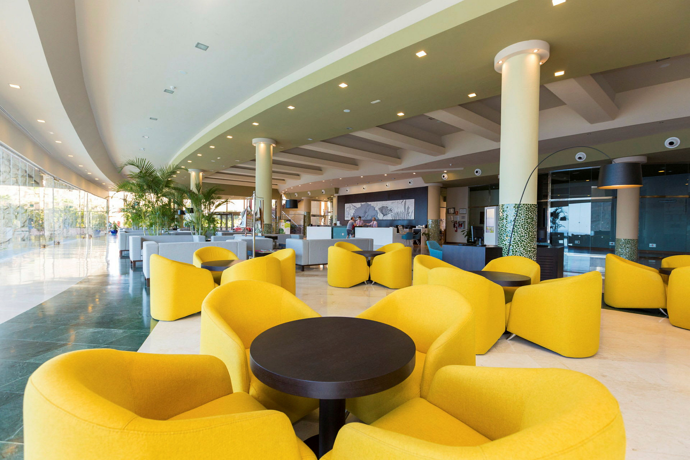 Modernin hotelliaulan sisustus keltaisilla lounge-tuoleilla ja sohvilla. (Tekoälyn luoma teksti)