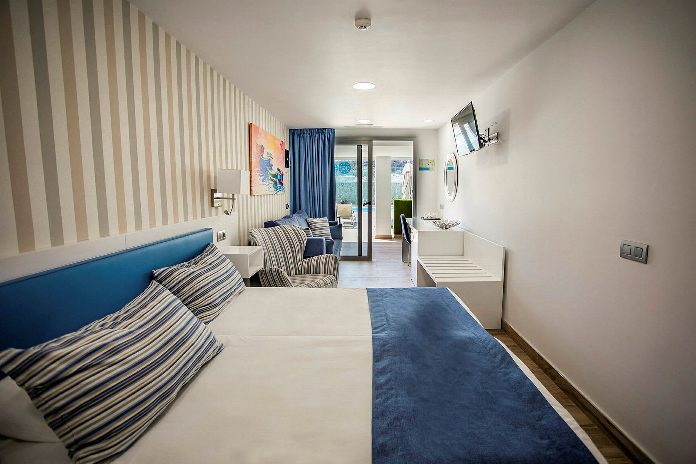 Hotellihuone, jossa on sänky, kaksi tuolia ja ikkuna pihalle. (Tekoälyn luoma teksti)