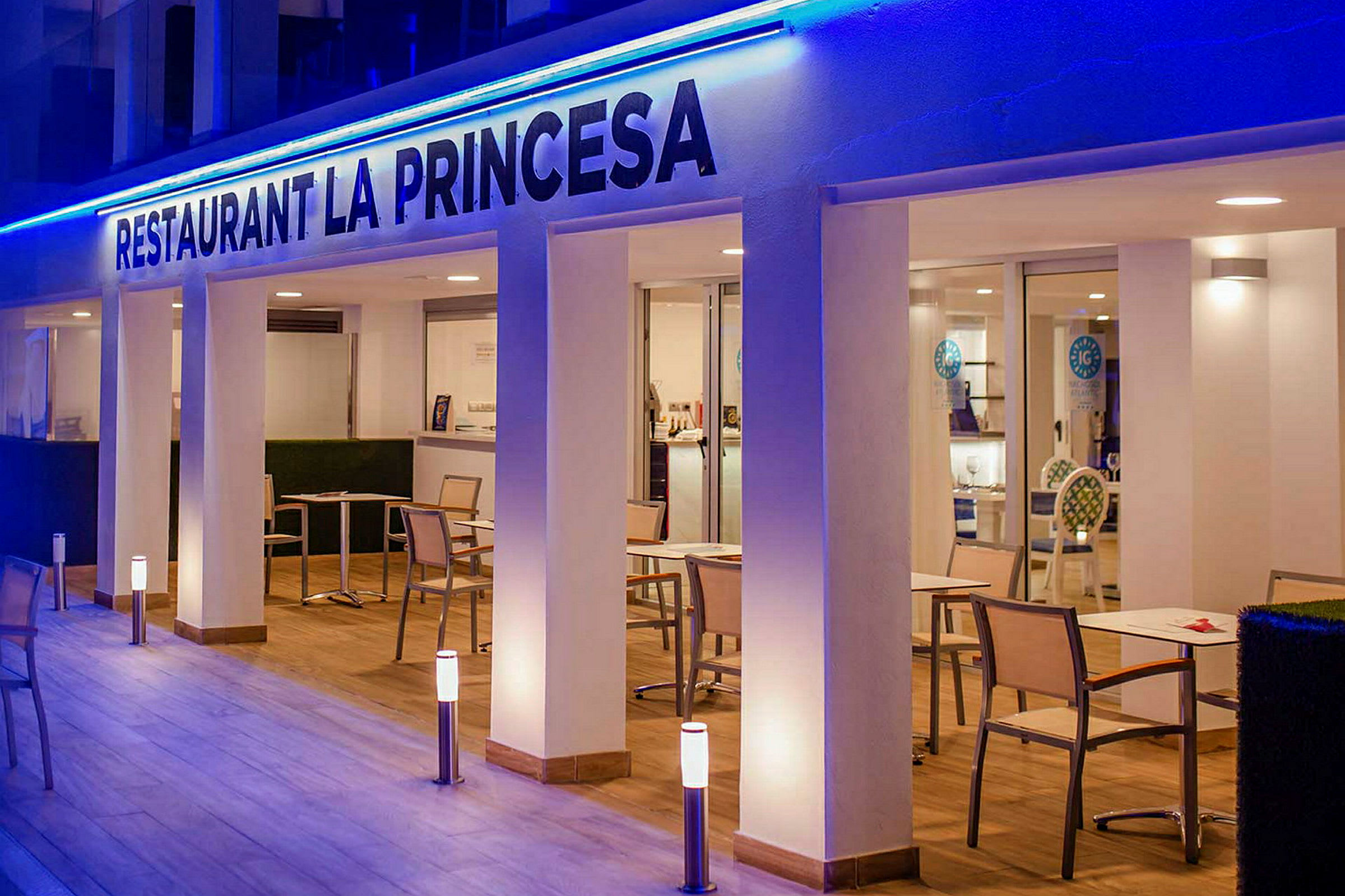 Ravintola La Princesa, jossa on pöytiä ja tuoleja valaistulla terassilla. (Tekoälyn luoma teksti)