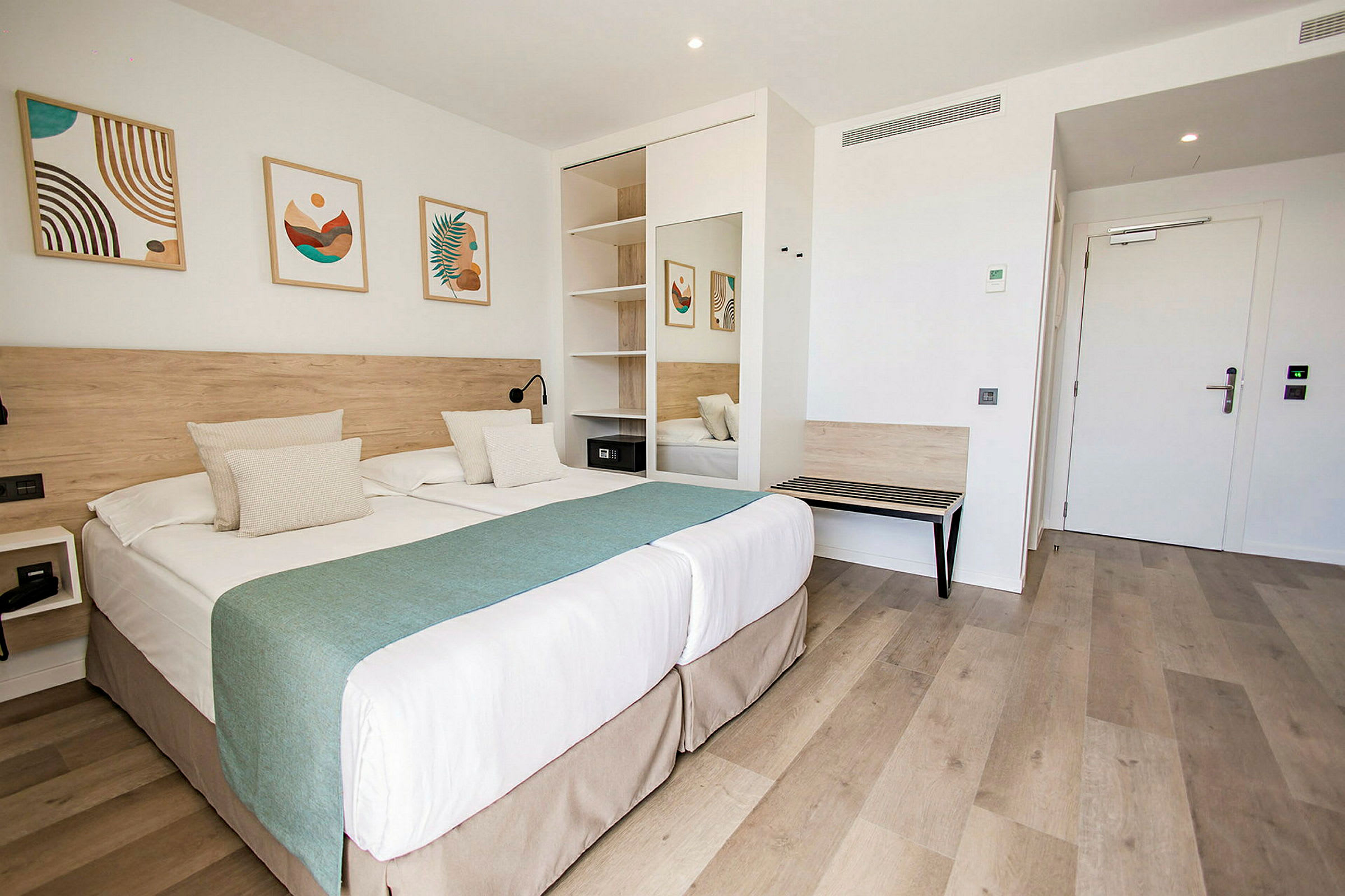 Hotellihuone, jossa parivuode, seinäkoristeita ja kaappi. (Tekoälyn luoma teksti)