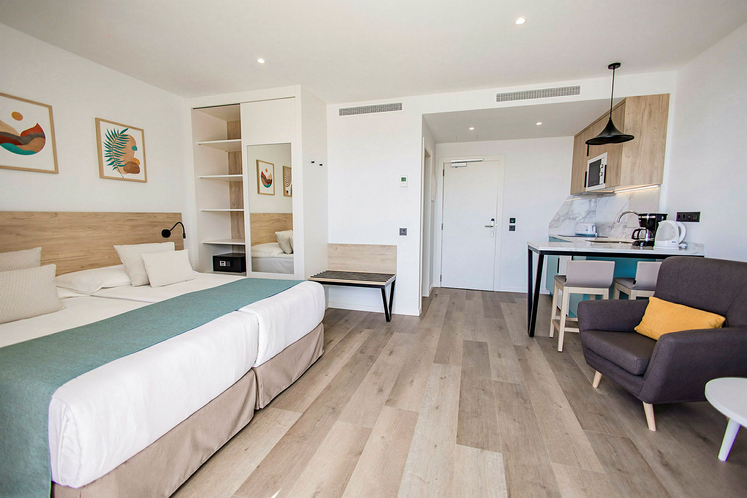 Moderni hotellistudio, jossa on parivuode, oleskelualue ja keittokomero. (Tekoälyn luoma teksti)