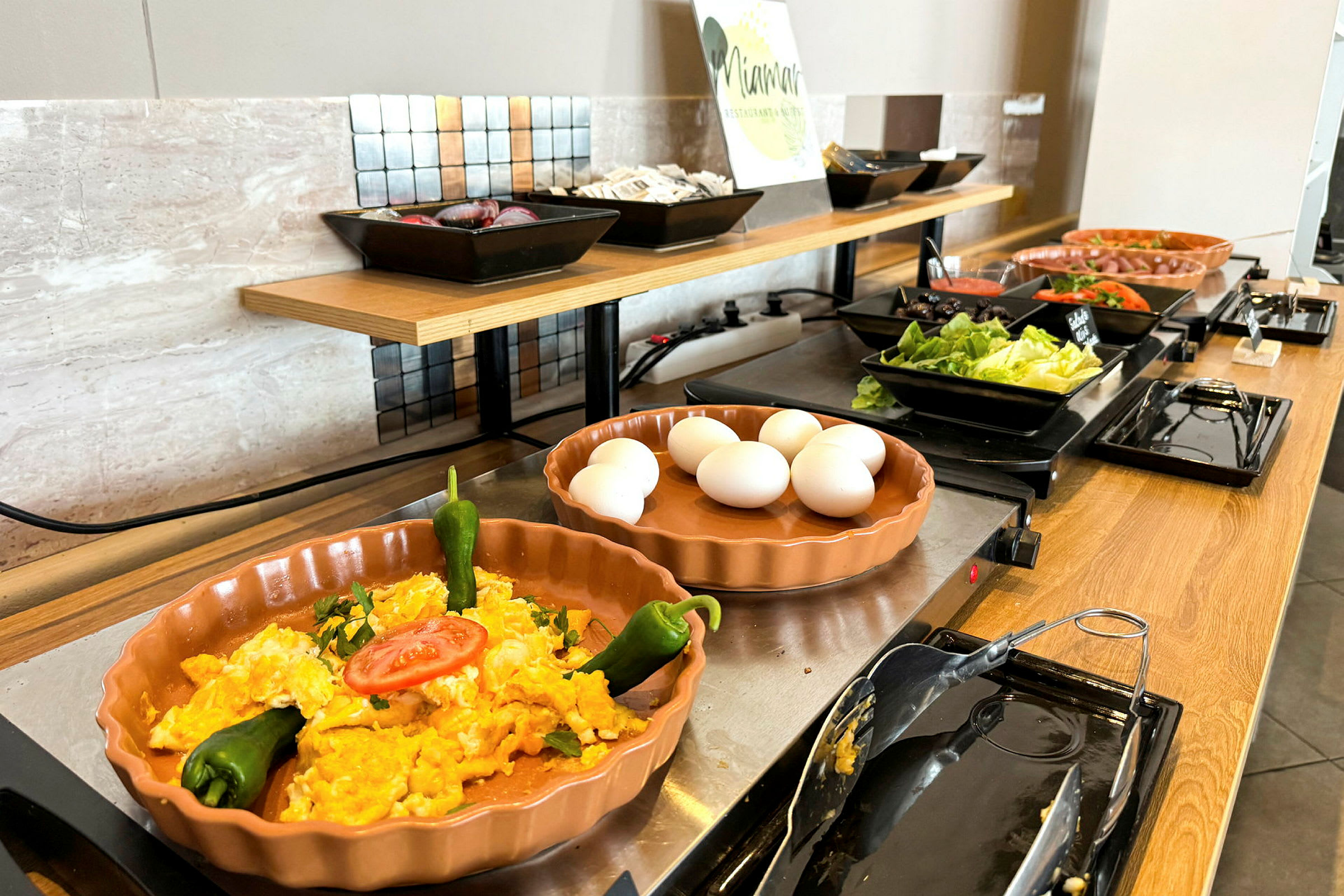 Buffet, jossa munia, vihanneksia ja salaattiaineksia. (Tekoälyn luoma teksti)