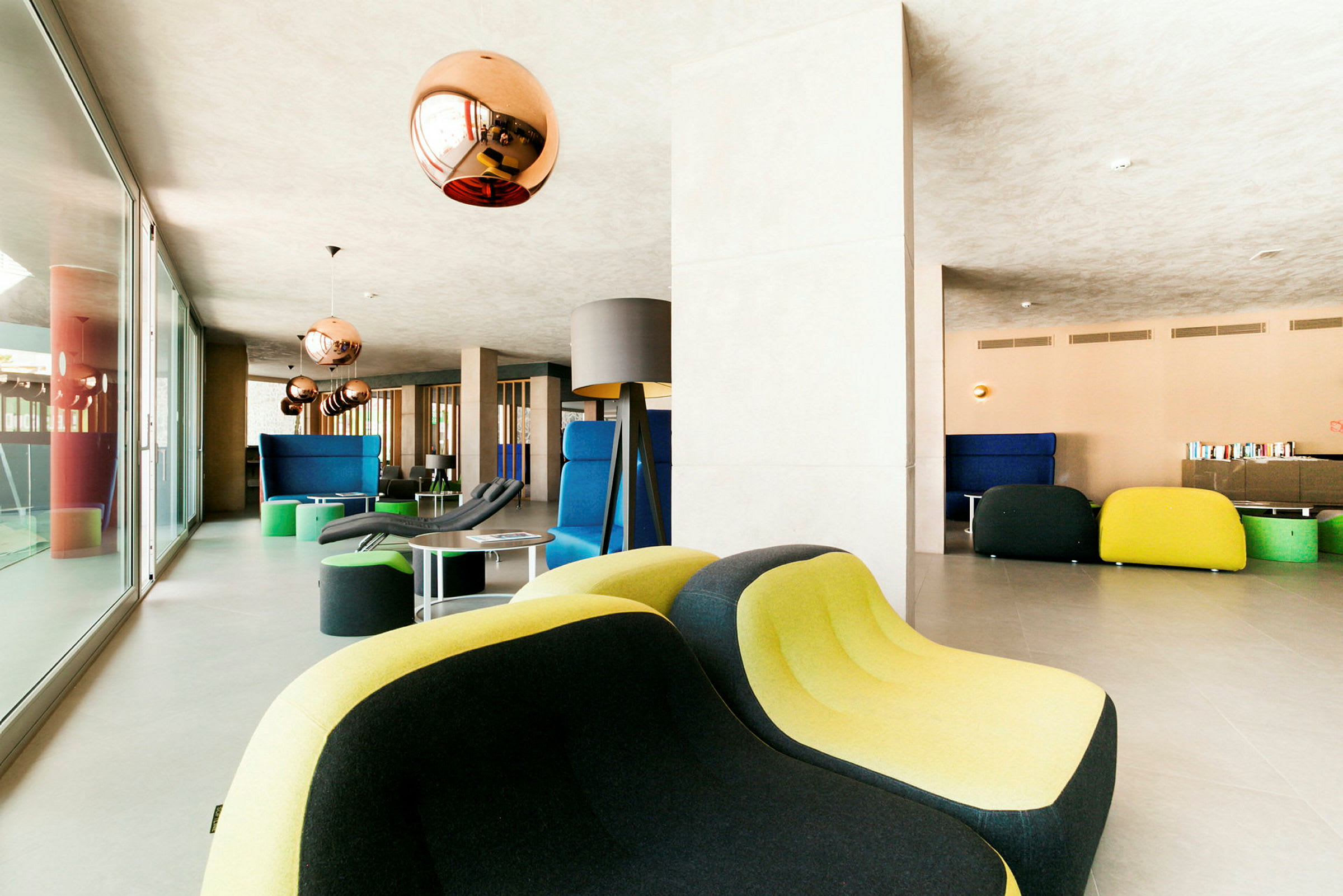 Moderni lounge, jossa värikkäitä huonekaluja ja kuparinvärisiä valaisimia. (Tekoälyn luoma teksti)