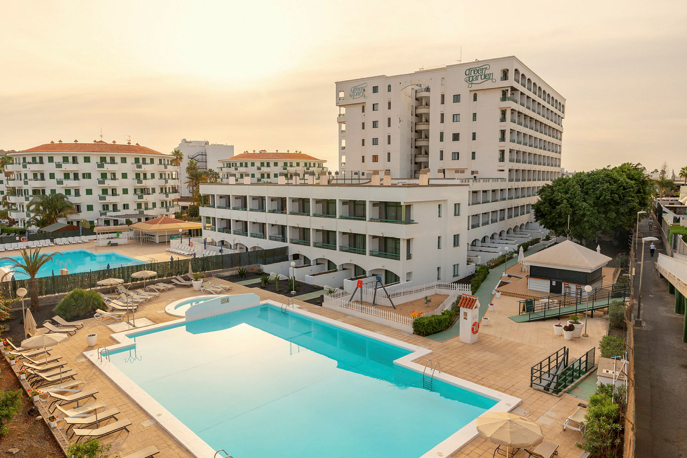 Hotellikompleksi, jossa on useita rakennuksia, kaksi uima-allasta ja aurinkotuoleja. (Tekoälyn luoma teksti)