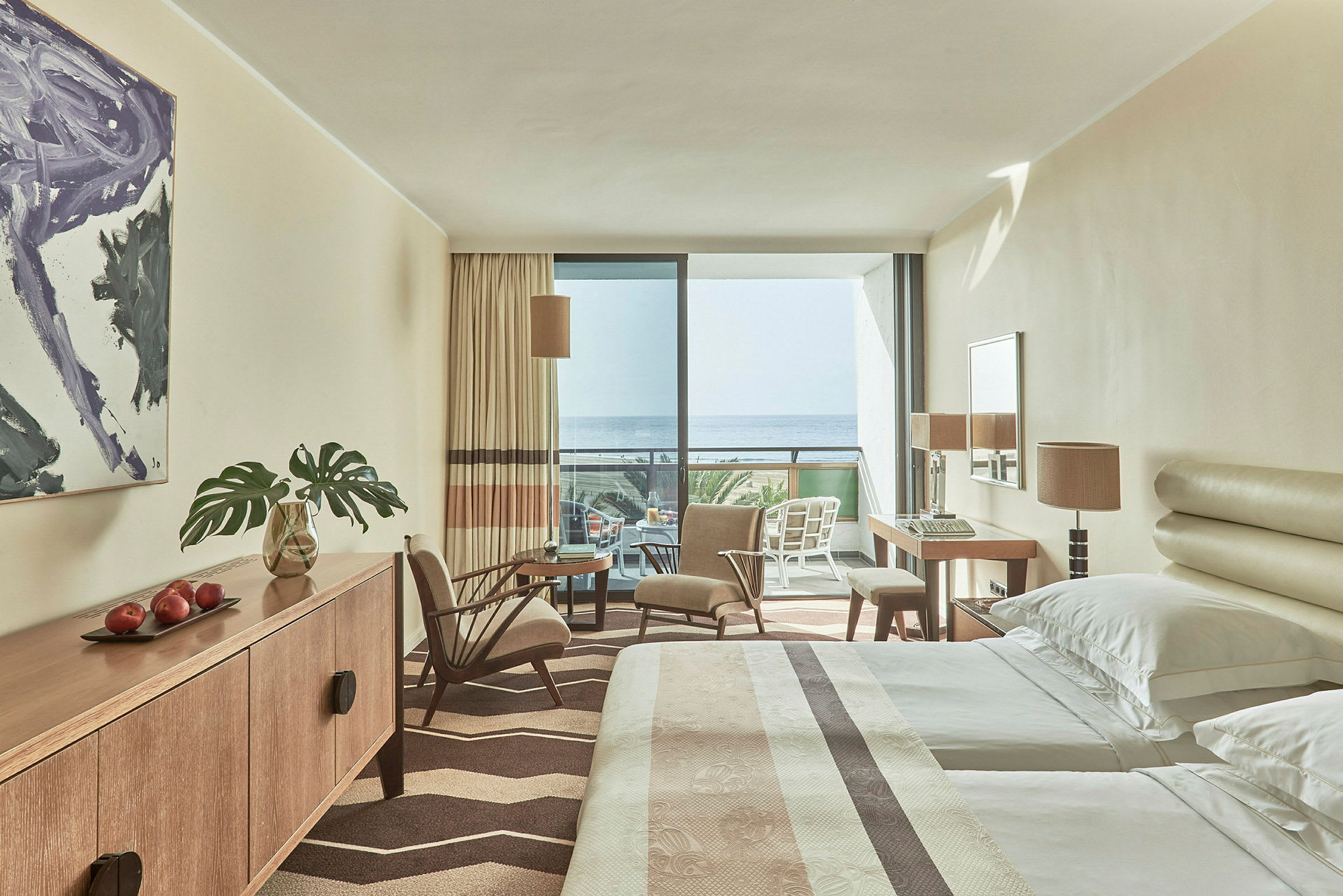 Hotellihuone, jossa vuoteet, istuimet ja parveke merinäköalalla. (Tekoälyn luoma teksti)