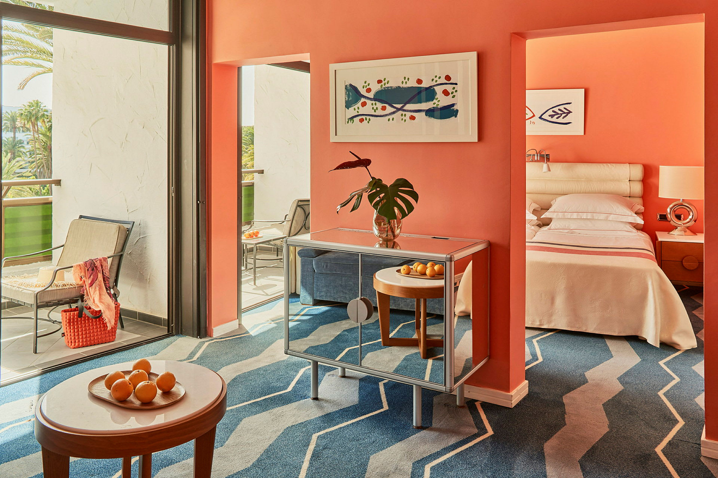 Hotellihuone, jossa on oranssi seinä, moderni sisustus, parveke ja nukuttu sänky. (Tekoälyn luoma teksti)