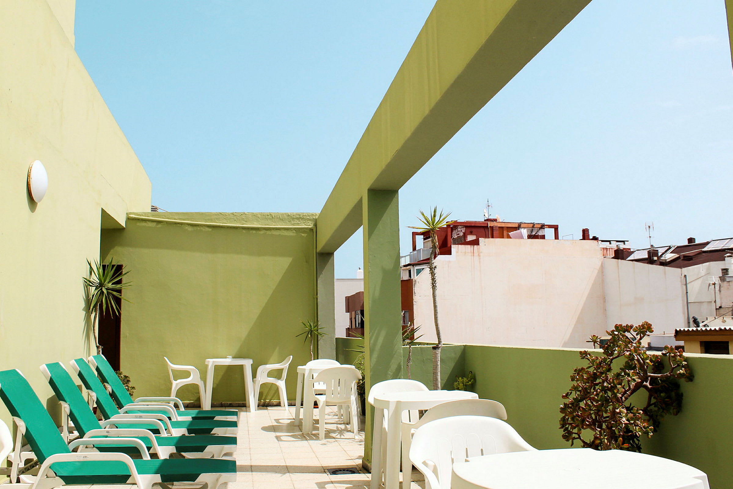 Terassi aurinkotuoleilla ja pöydillä, vihreiden seinien ympäröimänä. (Tekoälyn luoma teksti)
