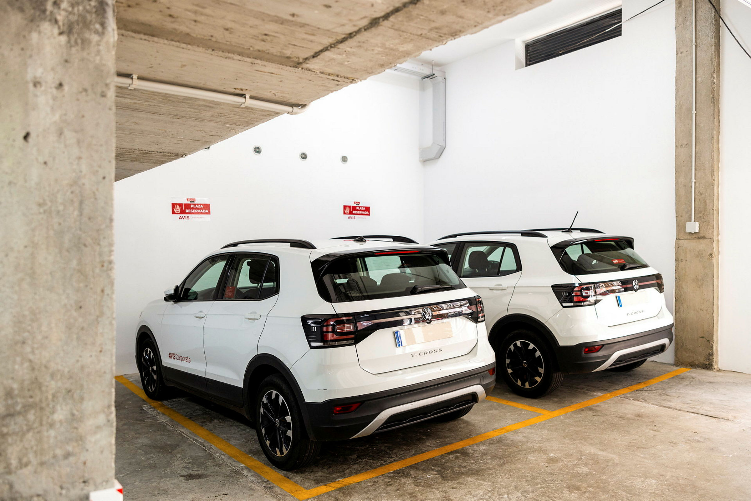 Kaksi valkoista SUV-autoa pysäköitynä maanalaisella pysäköintialueella. (Tekoälyn luoma teksti)
