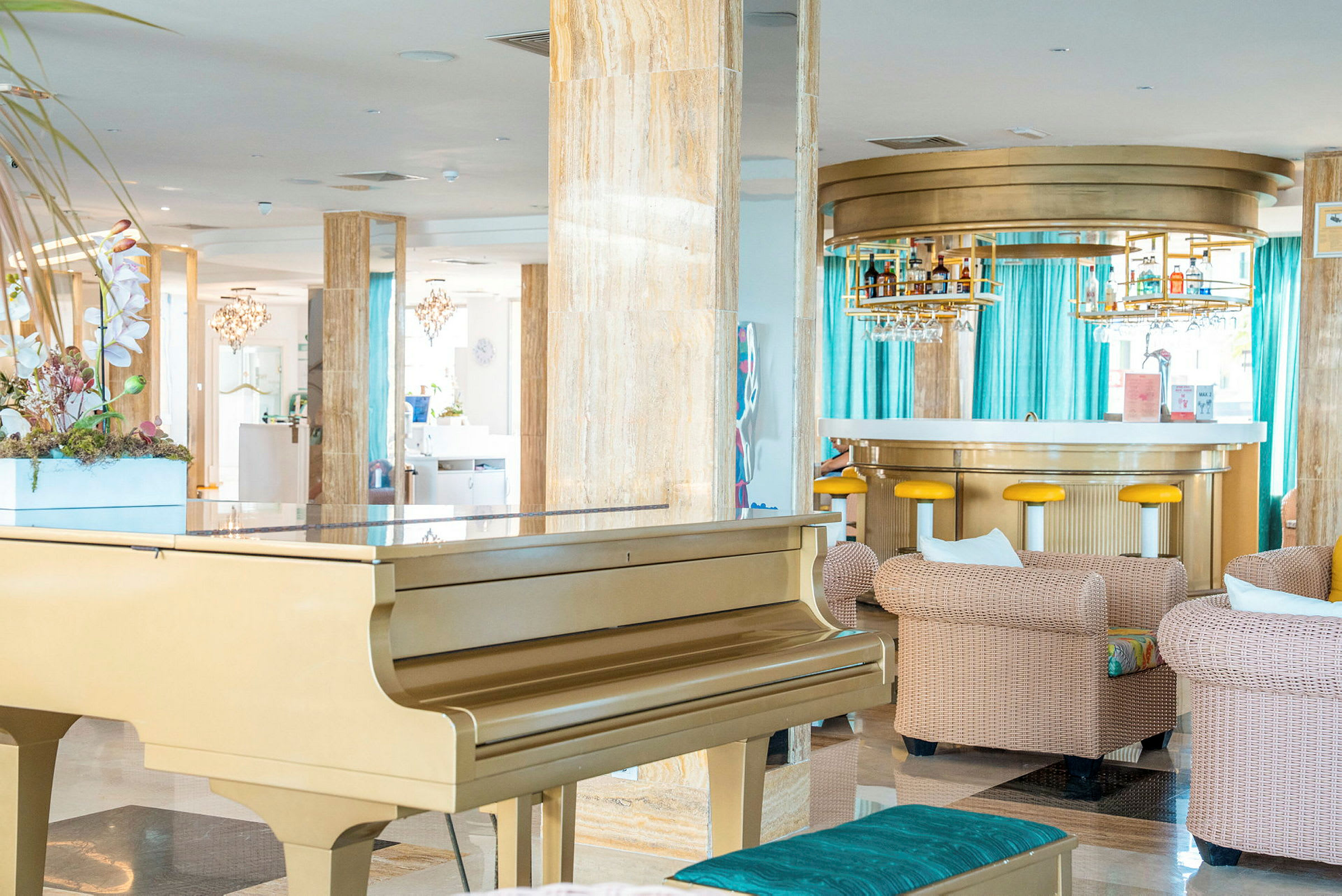 Tyylikäs hotellitila, jossa on kultainen piano, mukavat istuinryhmät ja moderni baari taustalla. (Tekoälyn luoma teksti)