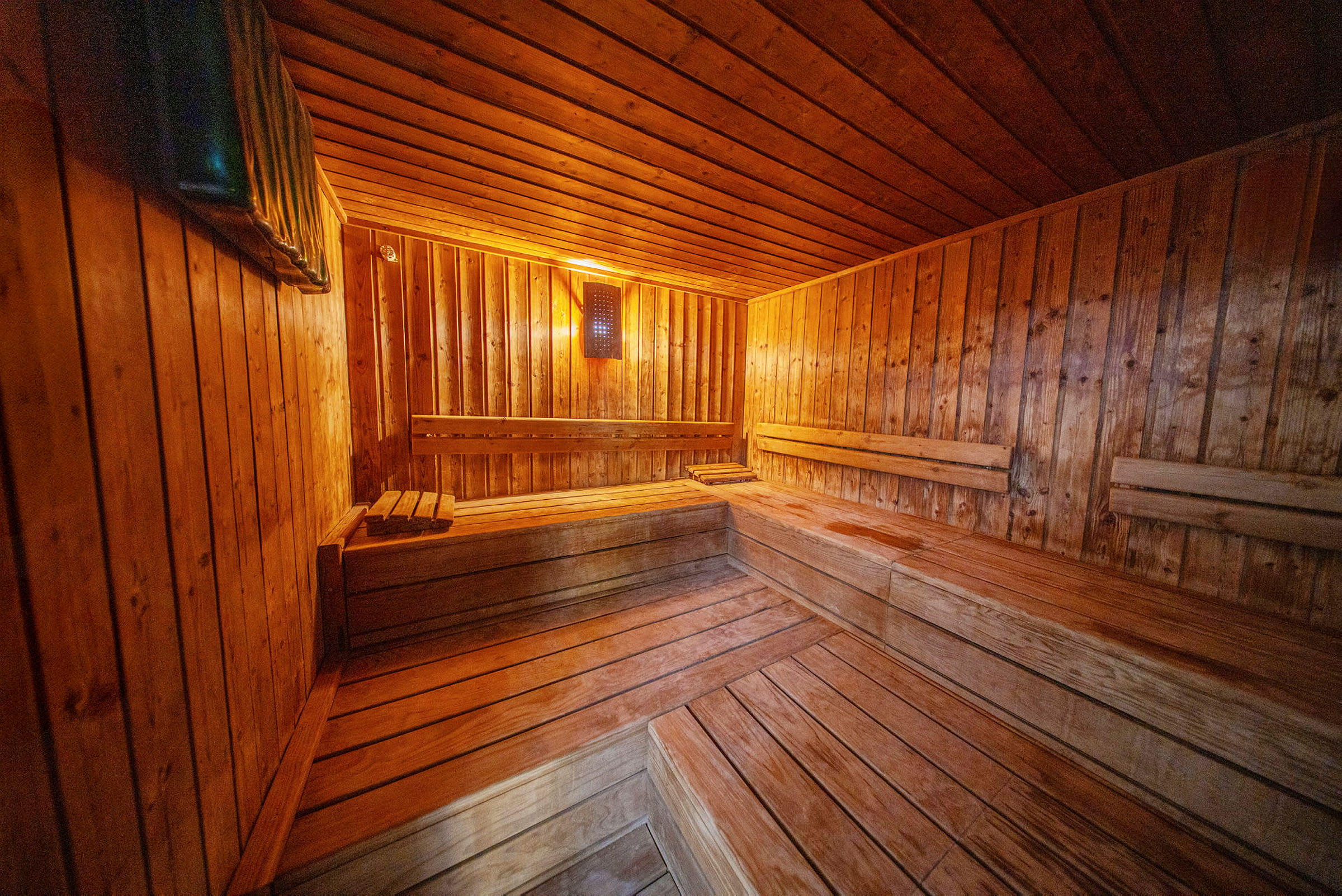 Puinen sauna, jossa on istuimia ja lämmin valaistus. (Tekoälyn luoma teksti)