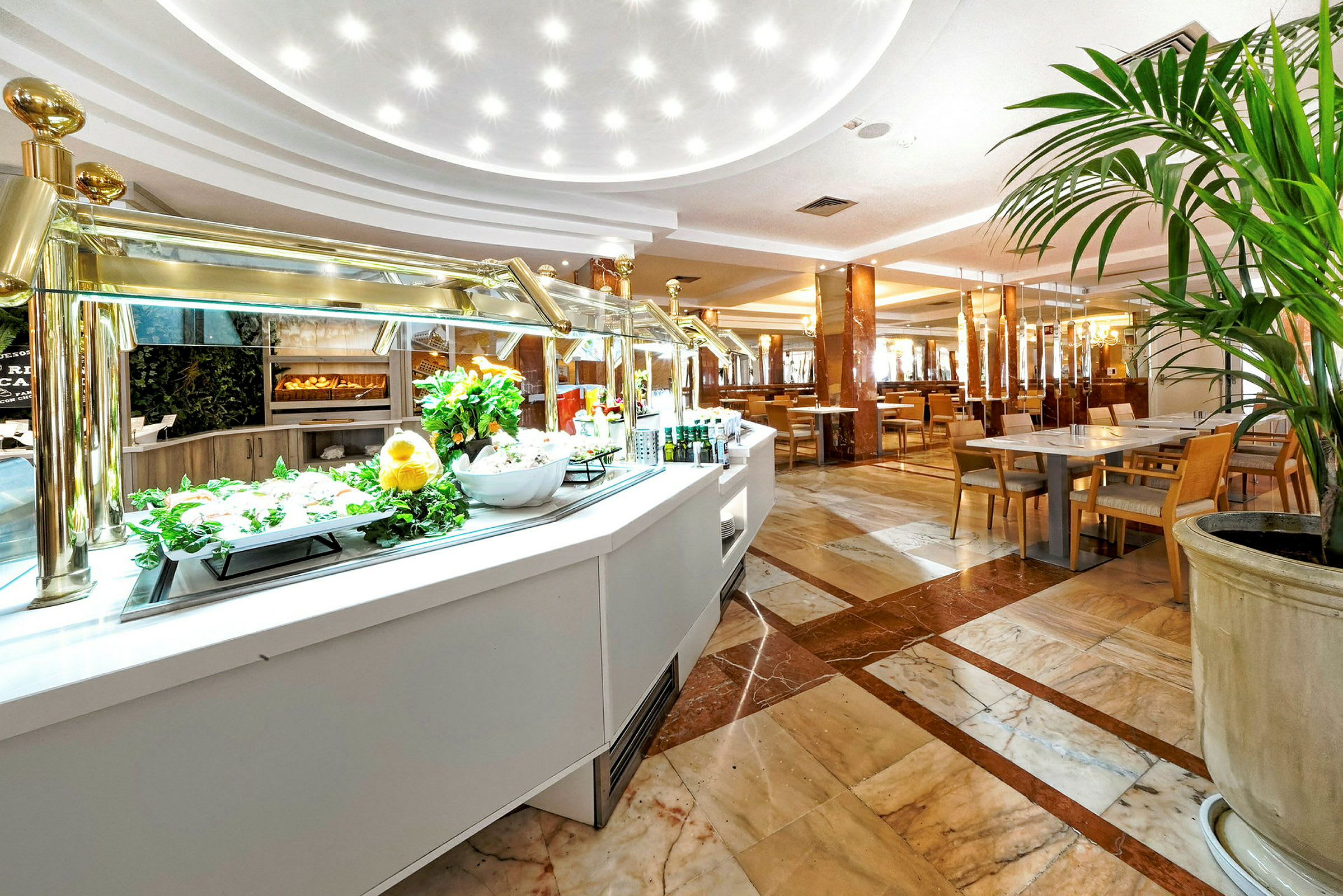 Buffet-alue, jossa valkoiset tasot, salaattia ja istumapaikkoja taustalla. (Tekoälyn luoma teksti)