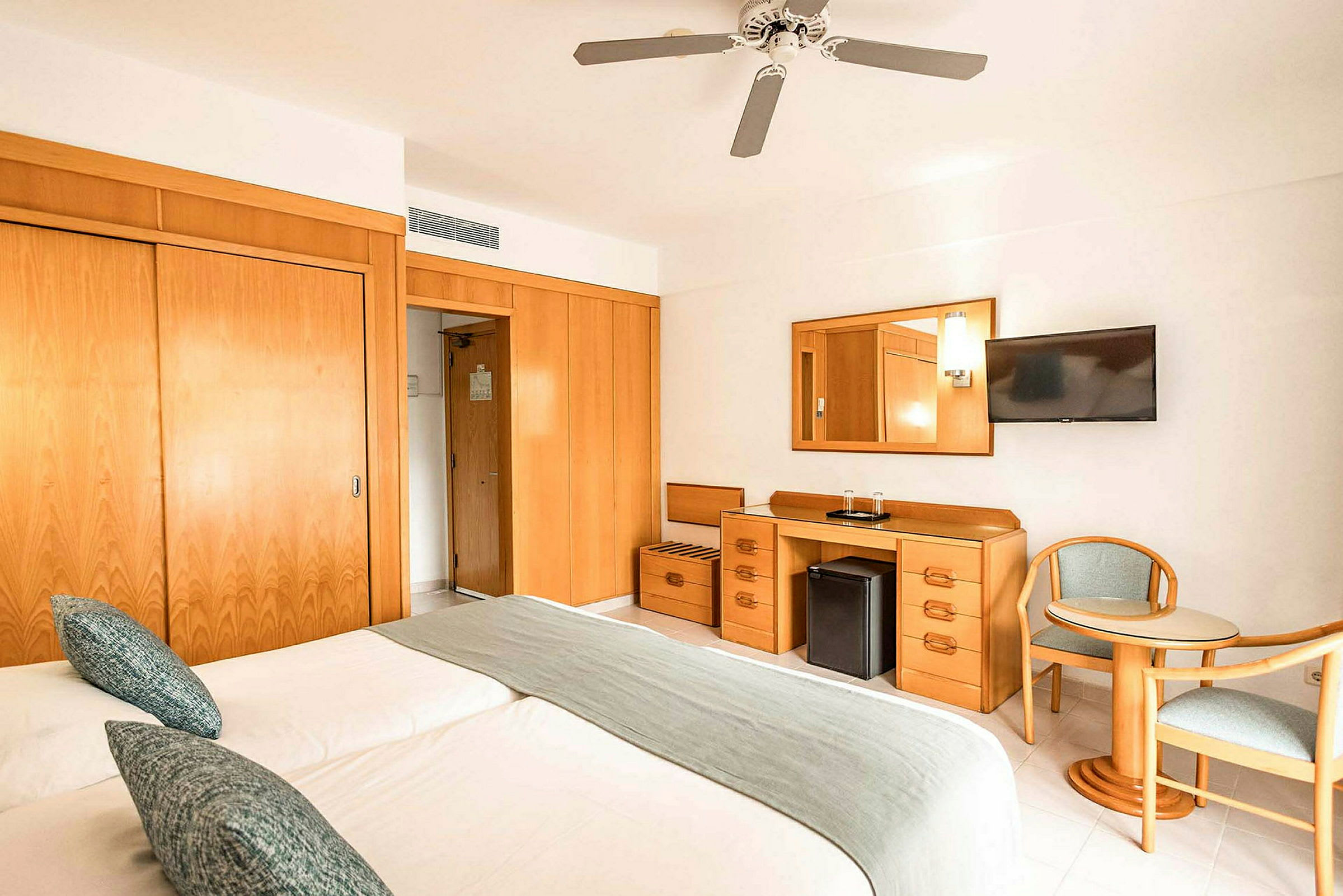 Hotellihuone, jossa kaksi sänkyä, pöytä, tuolit ja säilytyskalusteet. (Tekoälyn luoma teksti)