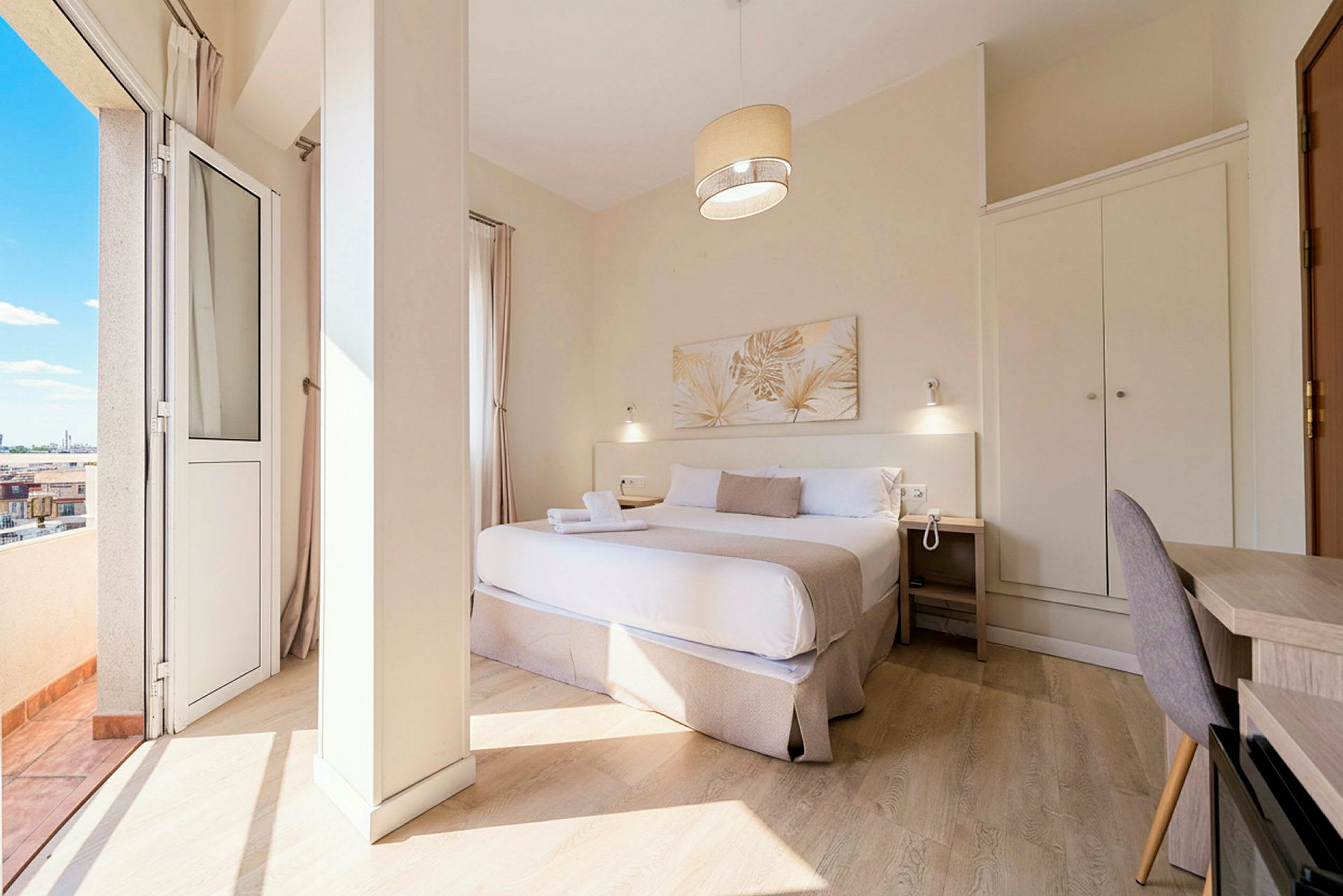 Hotellihuone, jossa on parivuode, yöpöytä, kirjoituspöytä ja vaatekaappi sekä parveke näköalalla. (Tekoälyn luoma teksti)
