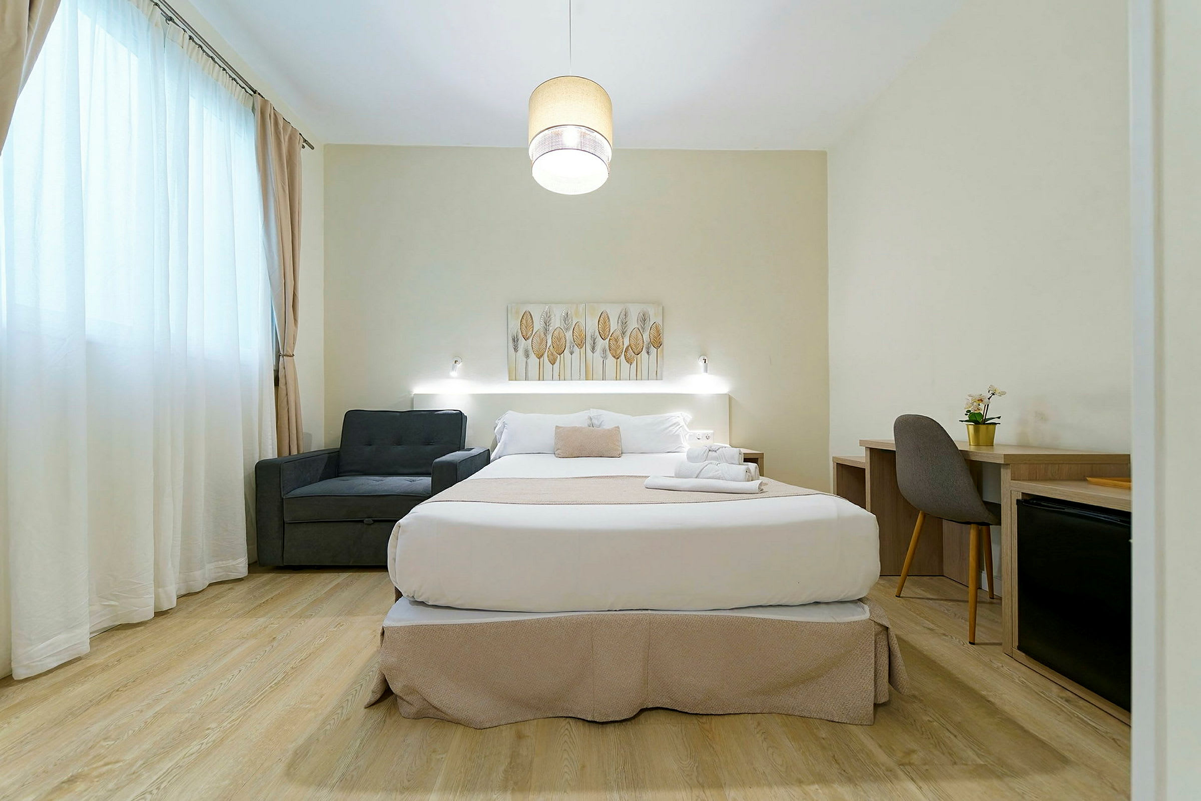 Hotellihuone, jossa on parivuode, nojatuoli ja kirjoituspöytä. (Tekoälyn luoma teksti)