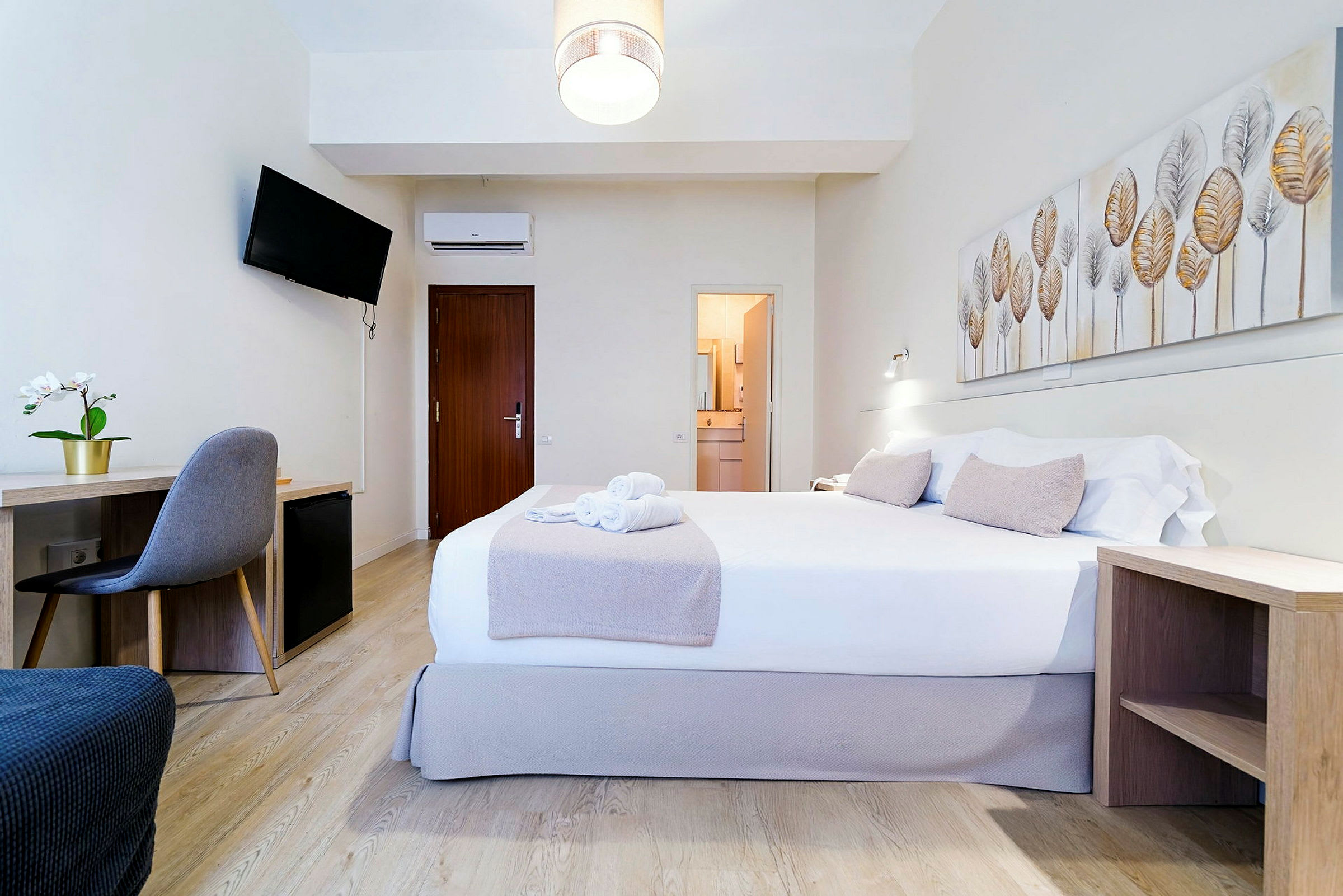 Hotellihuone, jossa on parivuode, kirjoituspöytä, tuoli ja seinäkoristeita. (Tekoälyn luoma teksti)